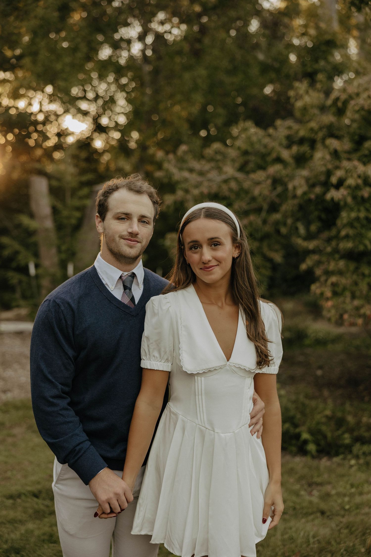 Couple poses together outdoors wearing coordinated casual outfits in natural lighting.