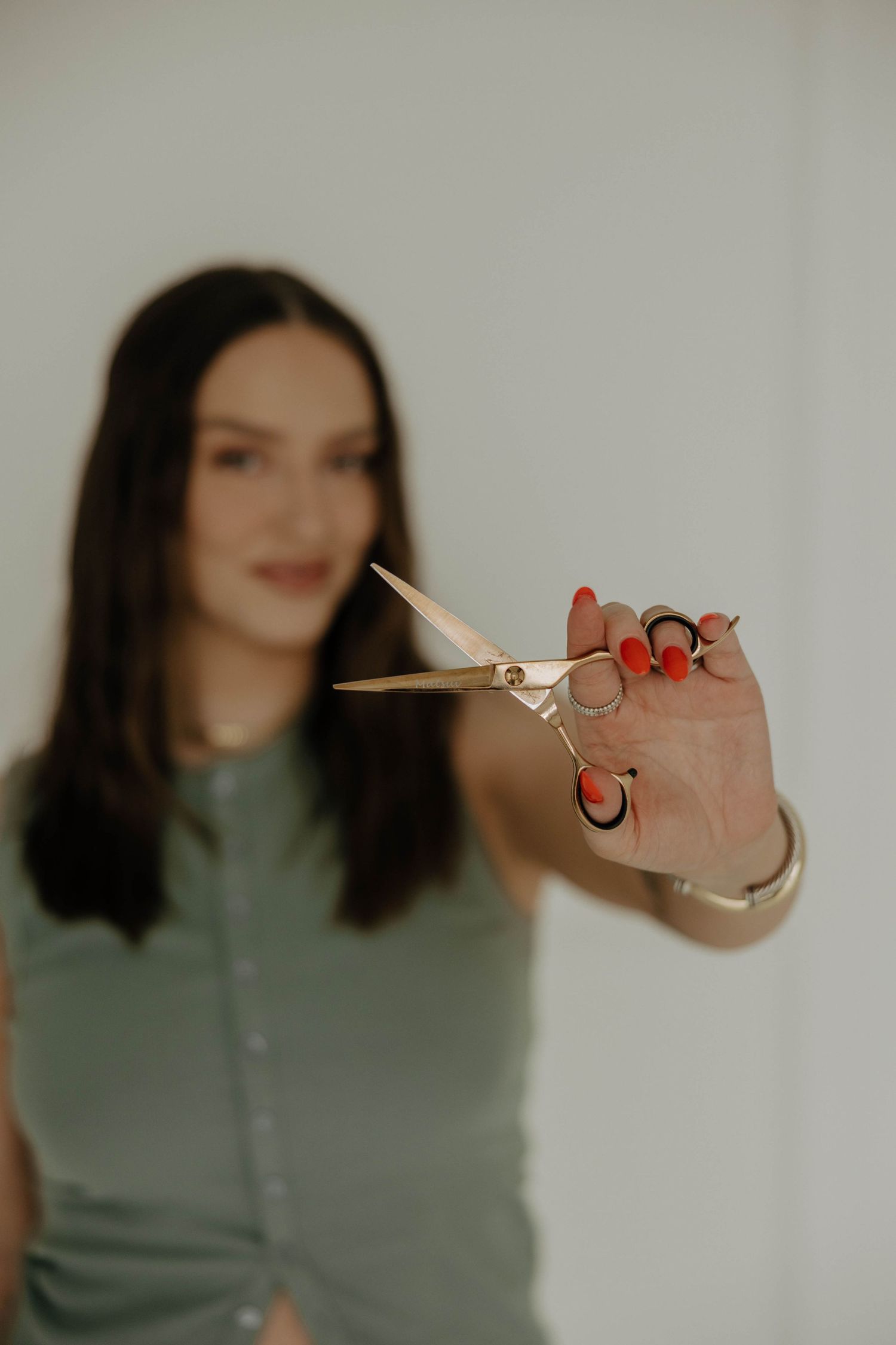A close-up shot of hands holding professional scissors against a light background.