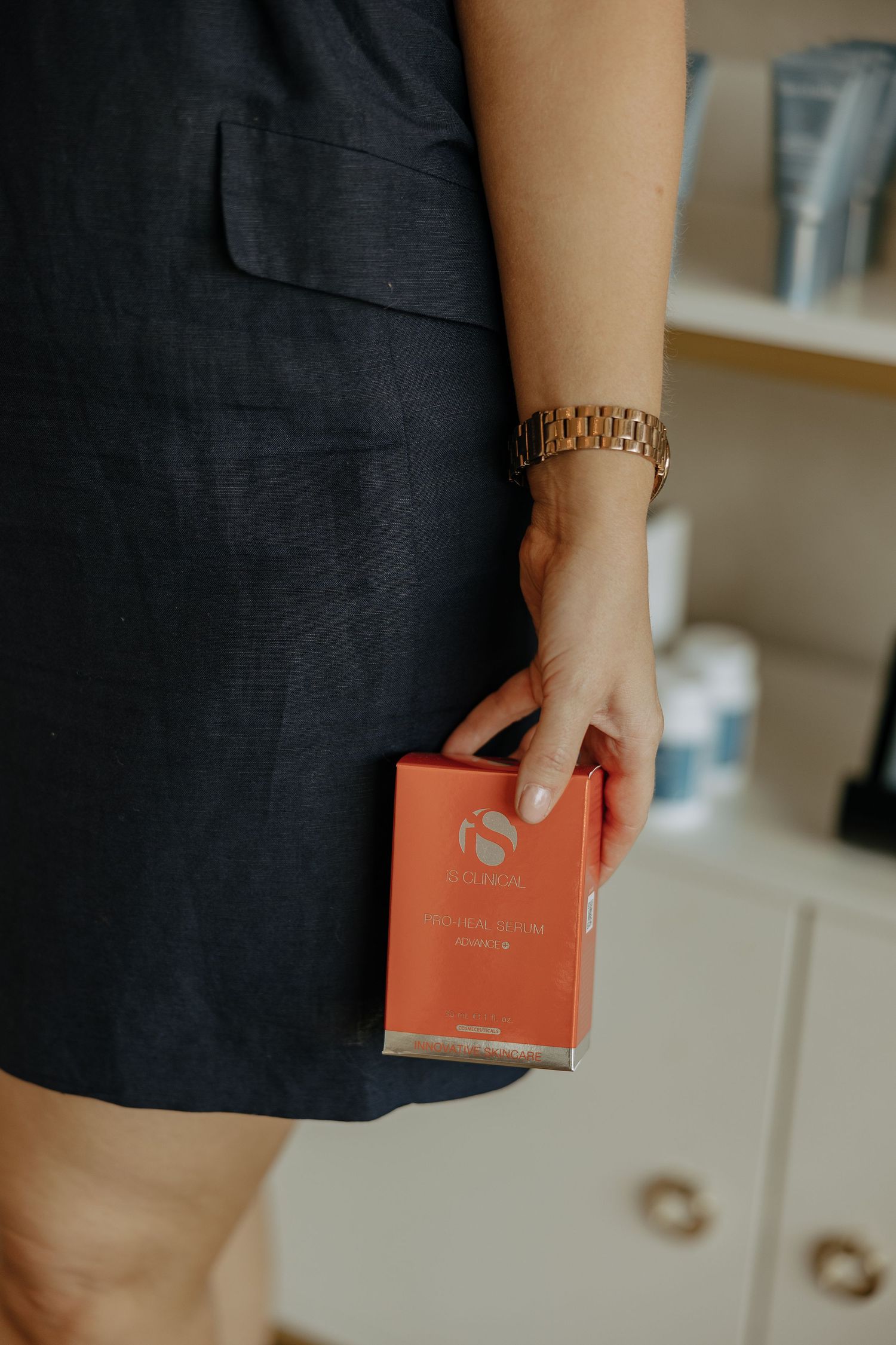 Hand holding coral colored product box in retail setting.
