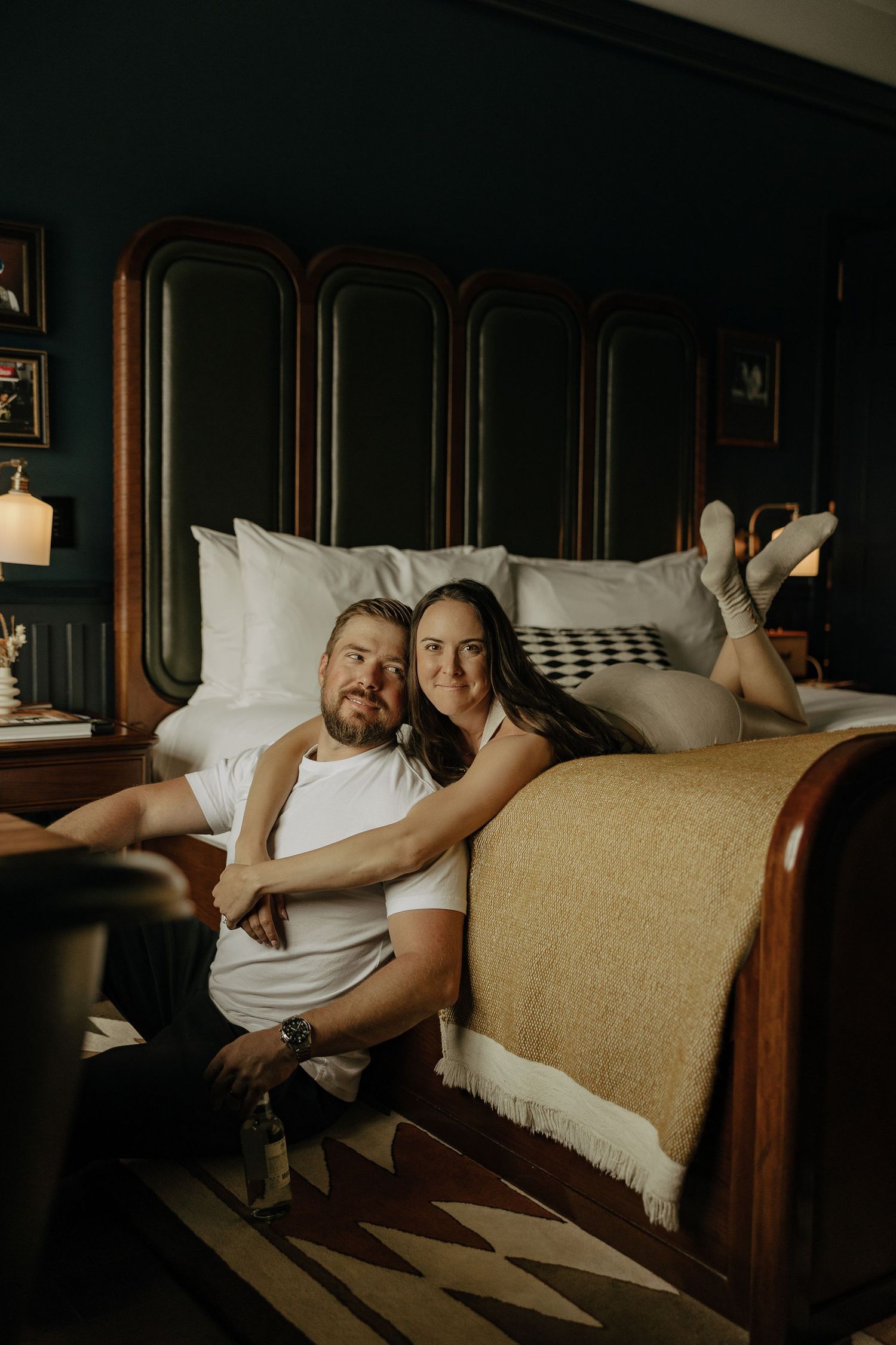 Intimate moment captured on antique bed with natural light streaming through window.