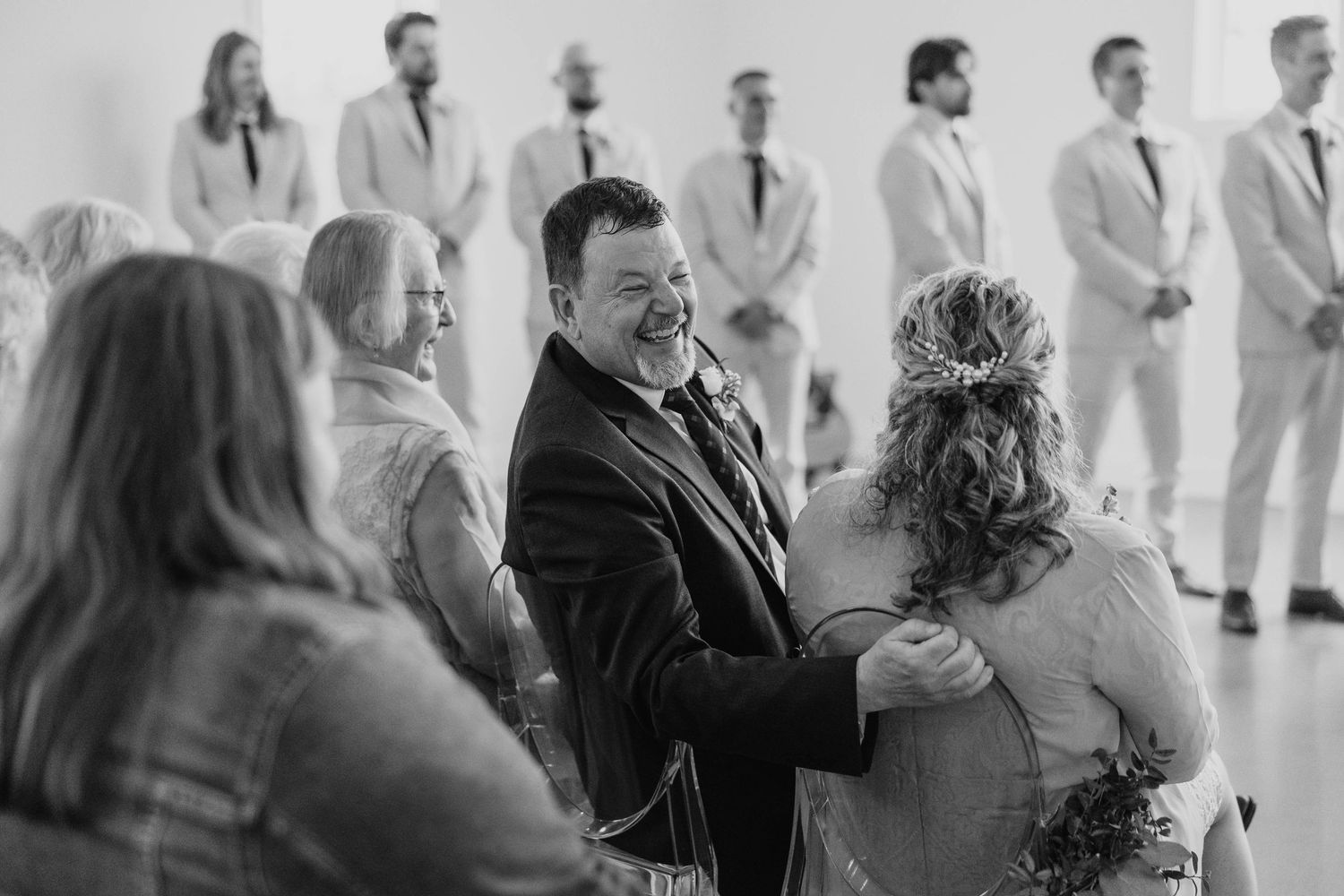 Wedding guests mingle in a bright indoor venue during a reception celebration.