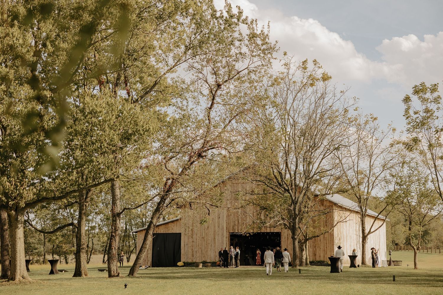Panoramic view of a countryside barn wedding venue surrounded by autumn trees.