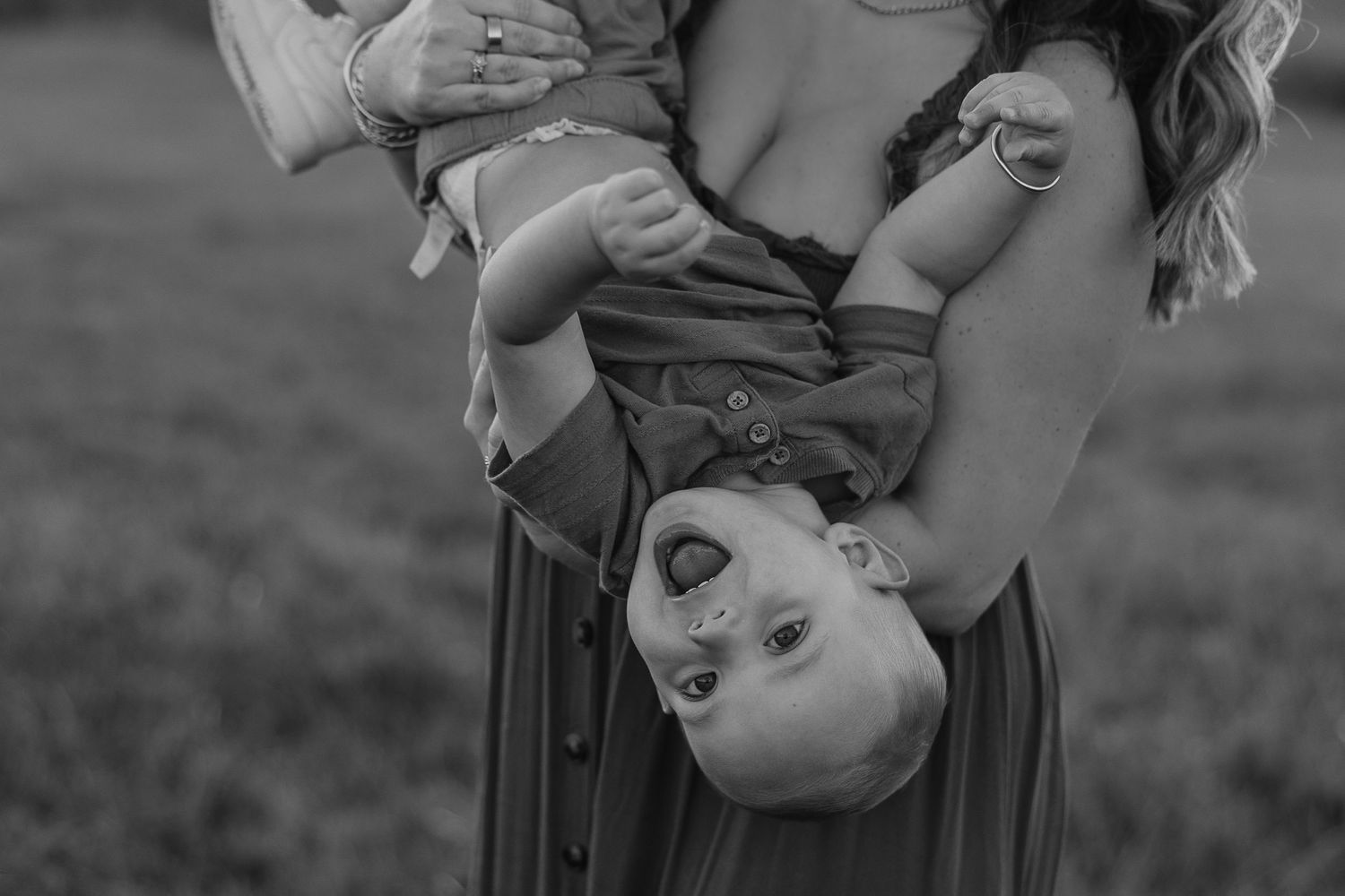 Black and white photo of mother and baby playing together on grass.