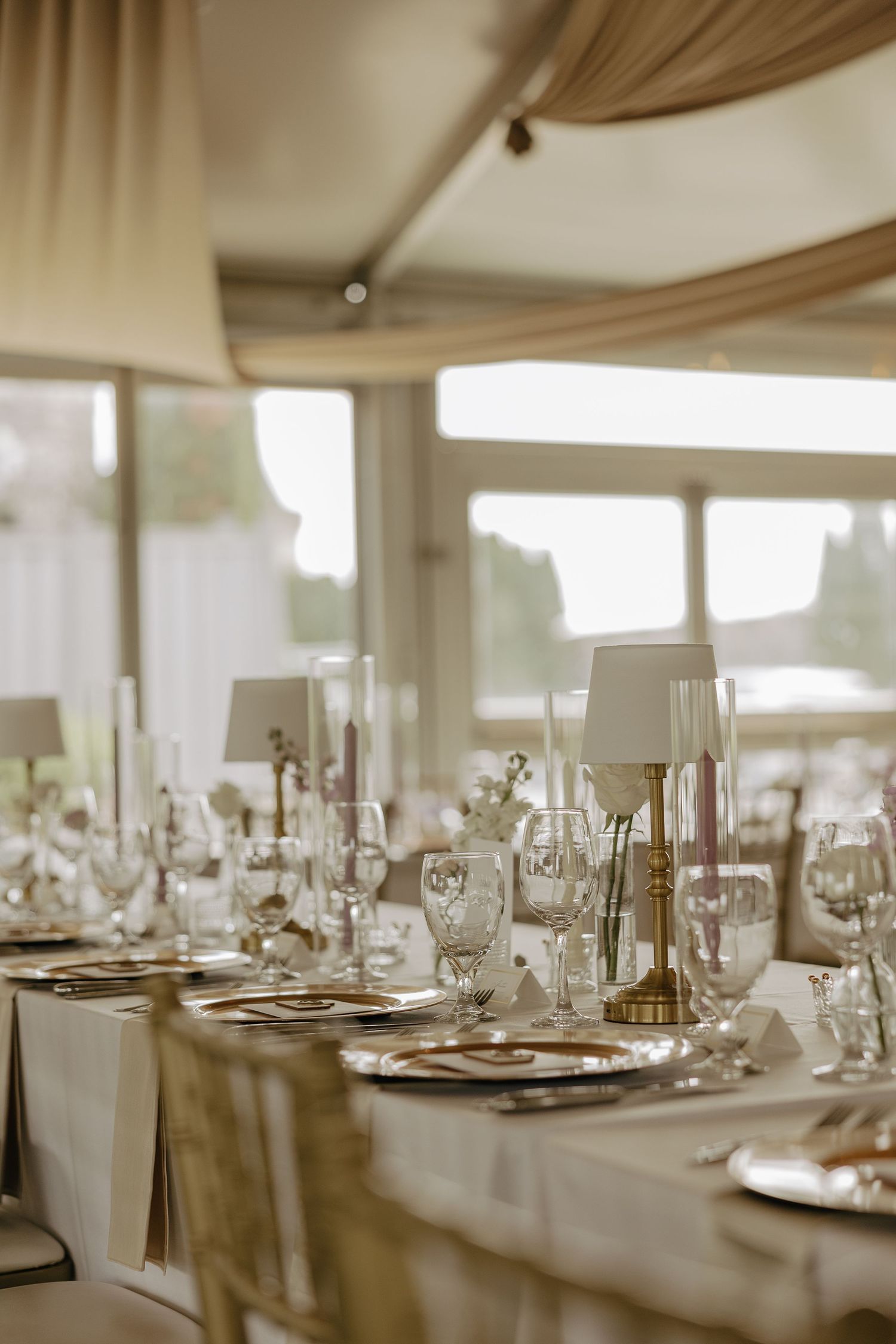 Wedding reception table details with white linens, gold accents, and elegant table lamps.