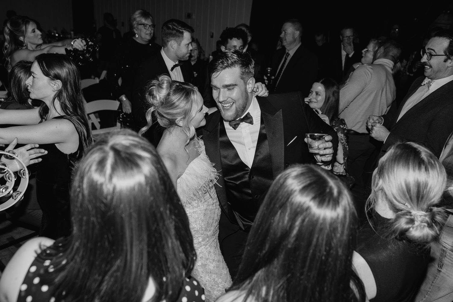 Black and white photo of guests dancing and mingling at an elegant formal event with people in evening attire.