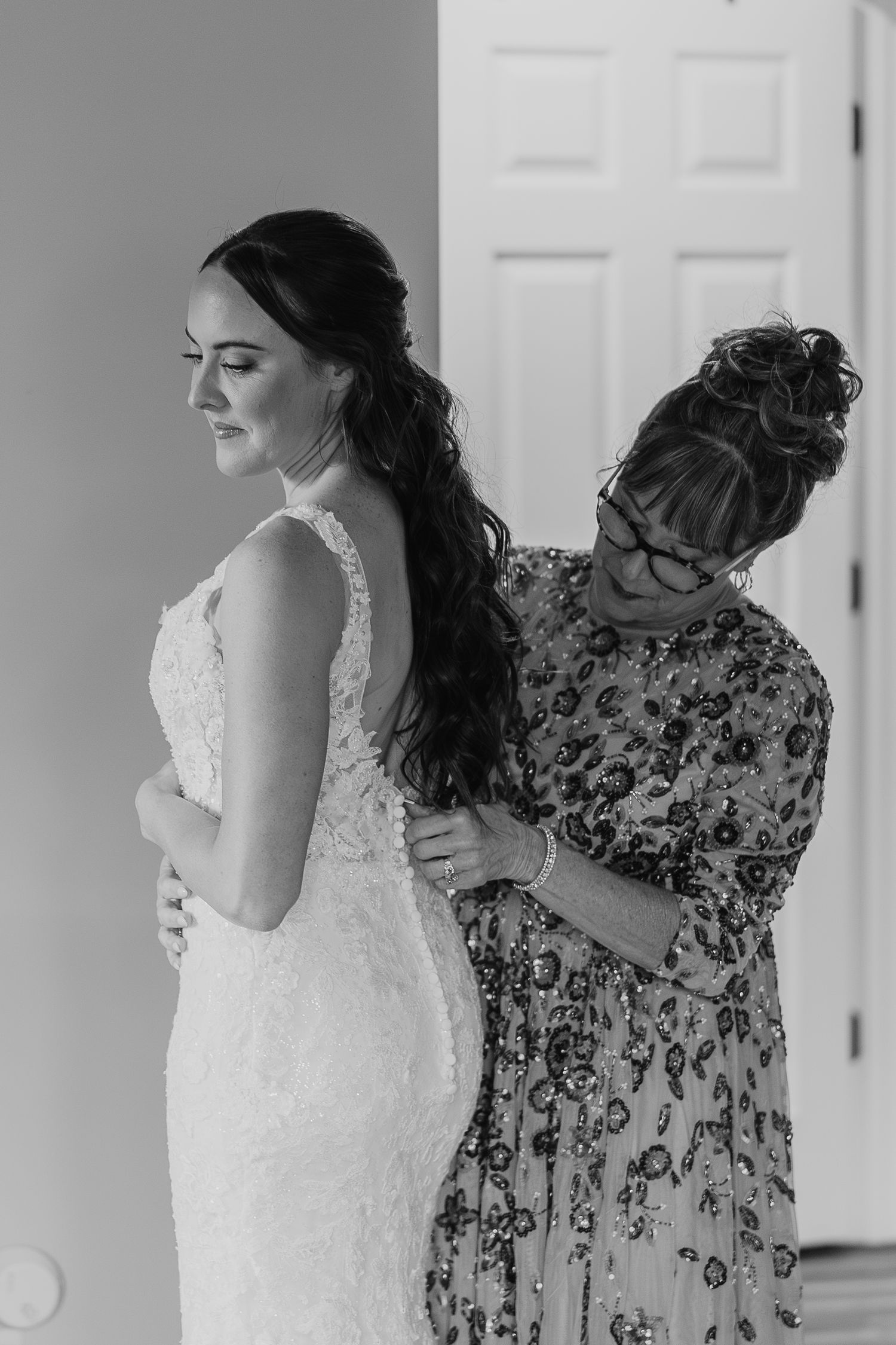 A delicate moment during wedding preparation with intricate lace dress details.