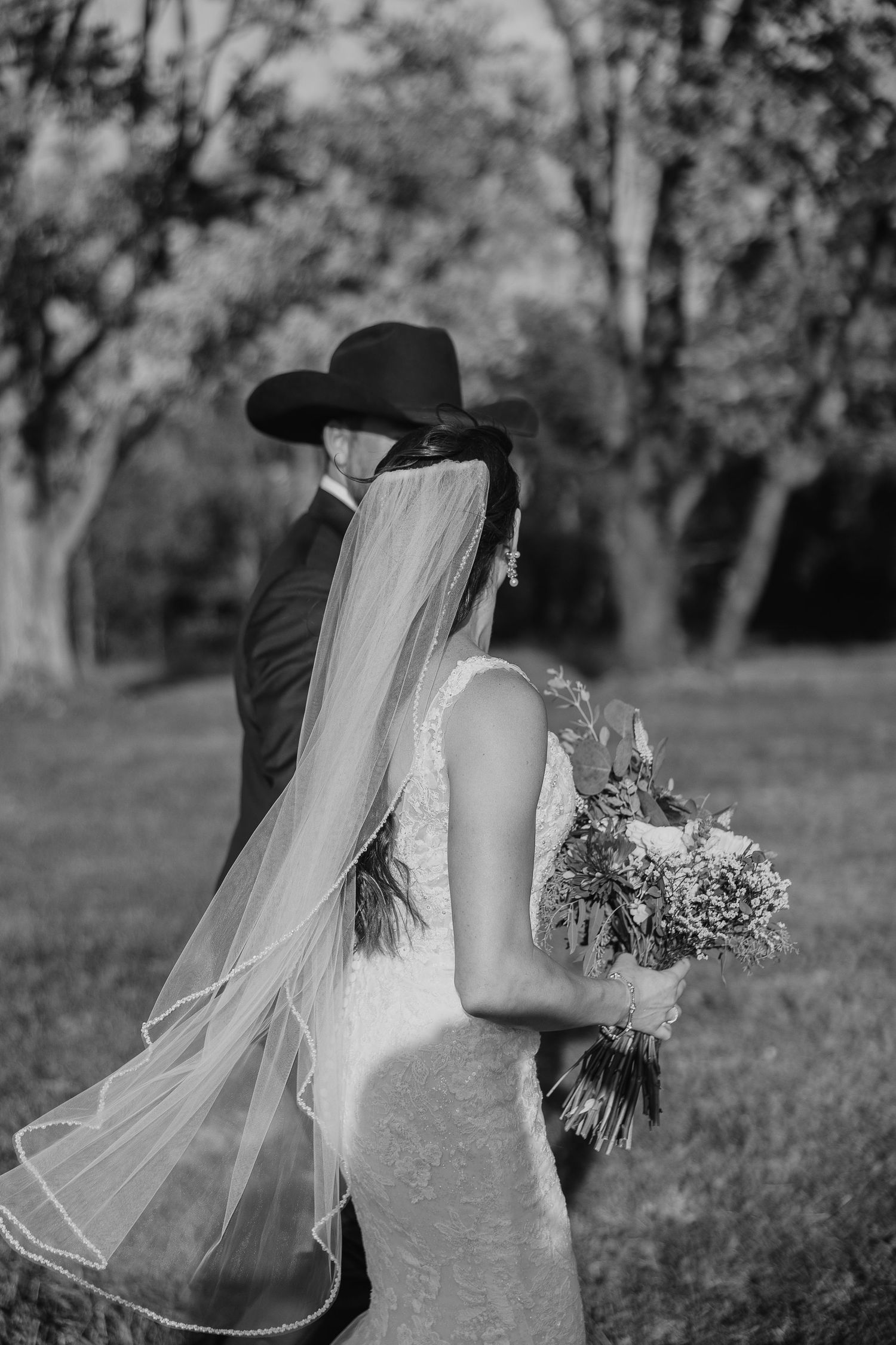 A romantic black and white portrait of newlyweds embracing in a garden setting.