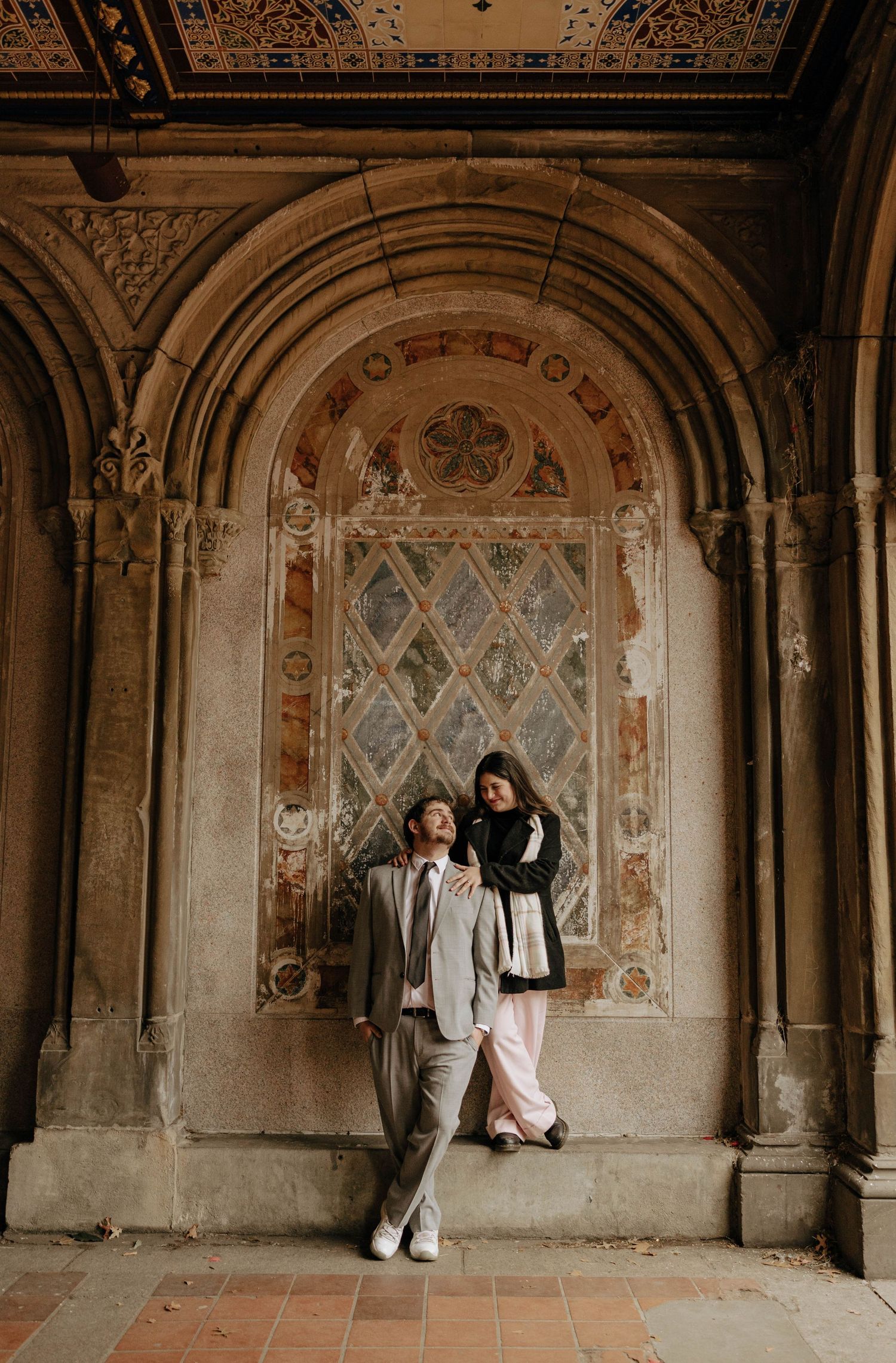 Romantic couple poses in five sequential shots under ornate stone archways at Bethesda Terrace in Central Park.