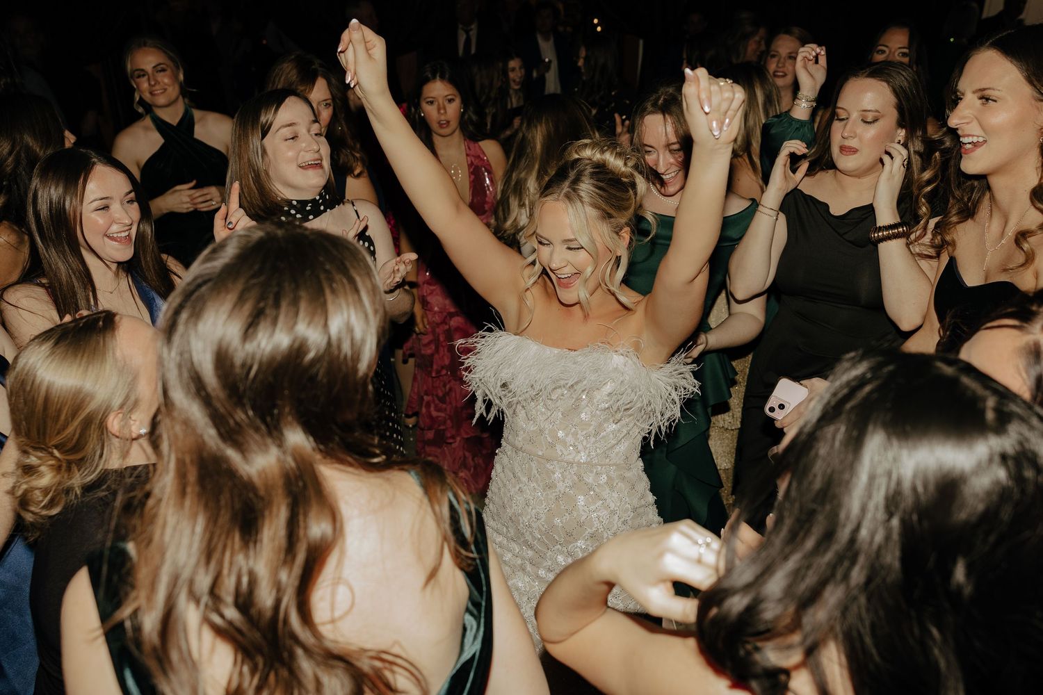 Large crowd of people dancing and celebrating at what appears to be a wedding reception or party.
