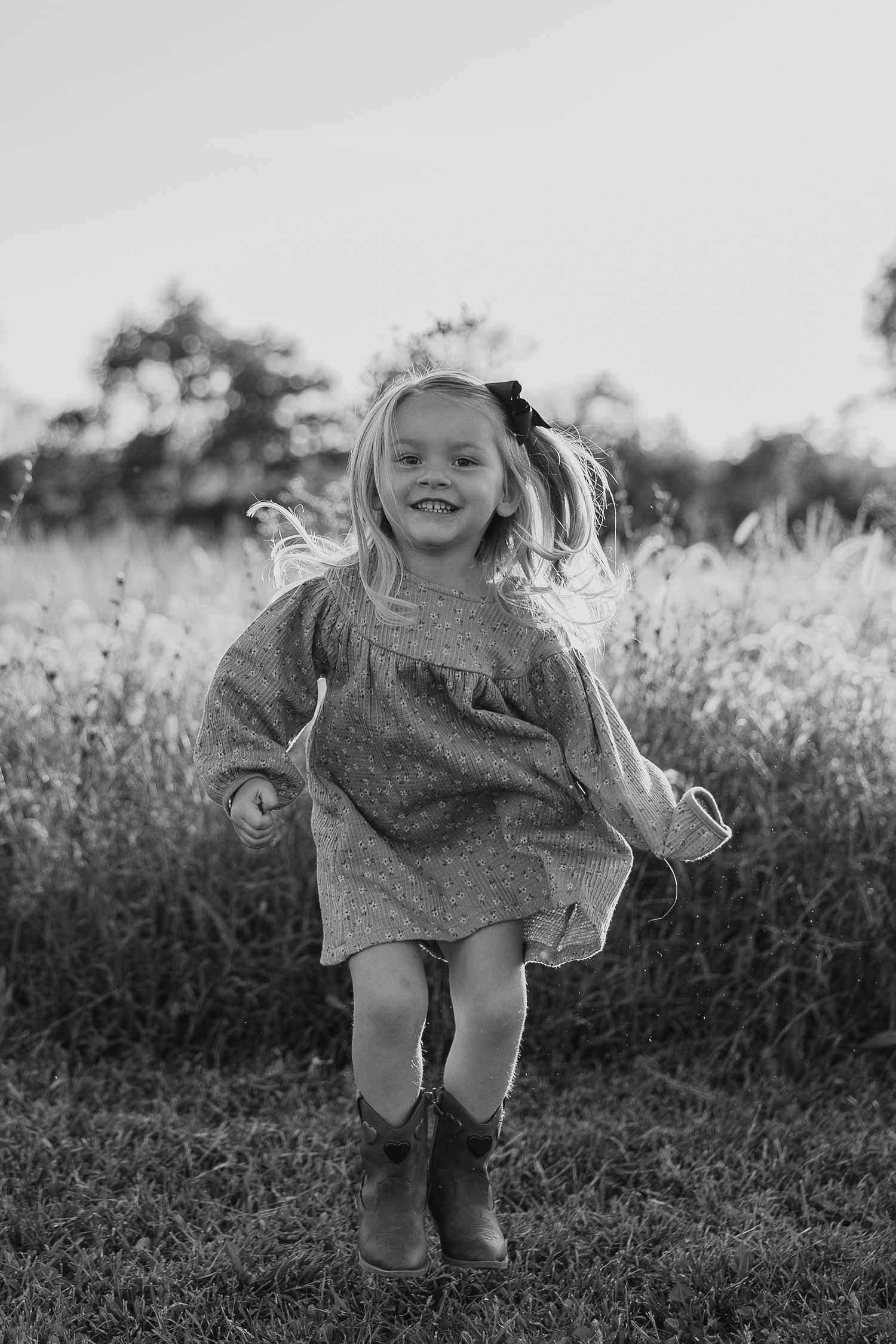 Young girl jumping and playing joyfully in a field during golden hour.