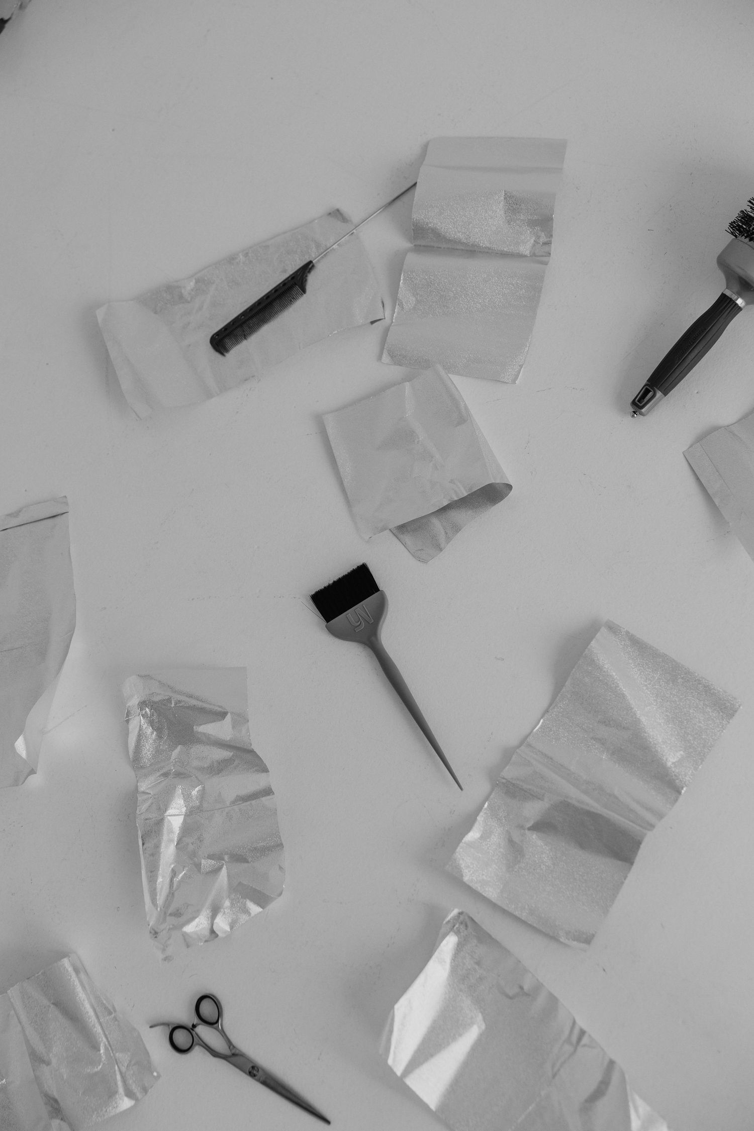 Various beauty and styling tools scattered on a white surface including scissors and papers.