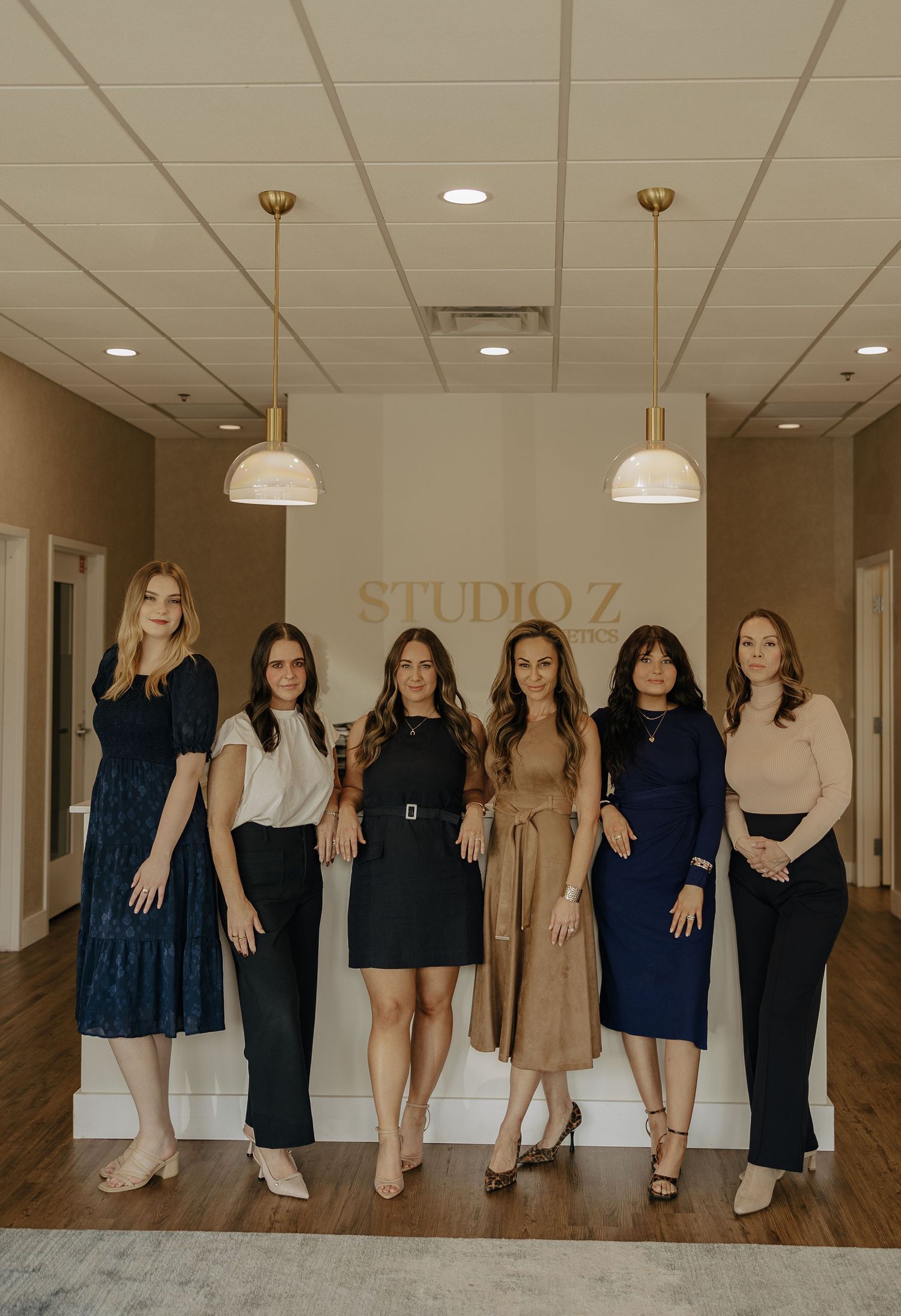 Full length group portrait of aesthetics team in coordinated business attire at Studio Z.
