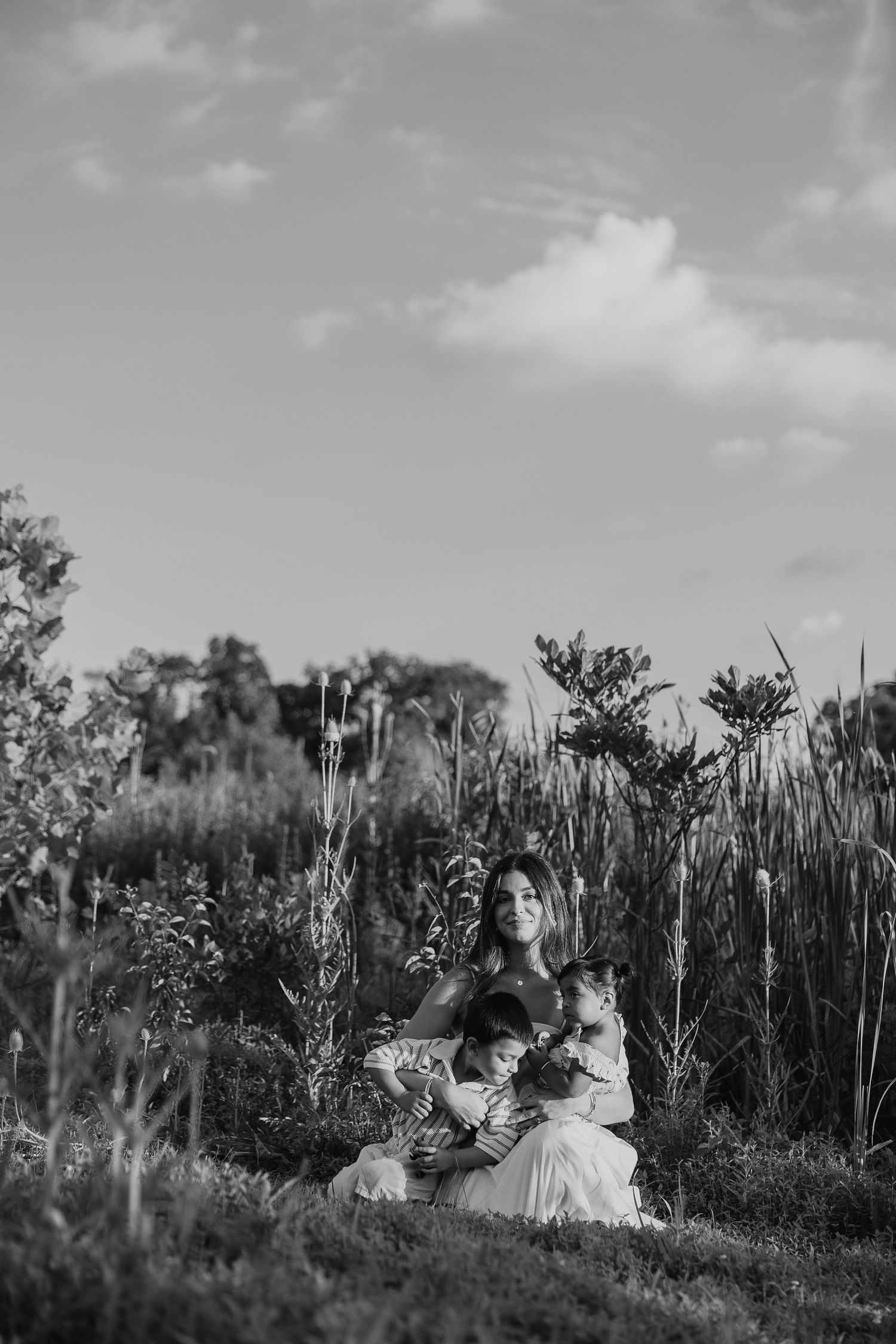 Family enjoying a tender moment together in a grassy field during golden hour.