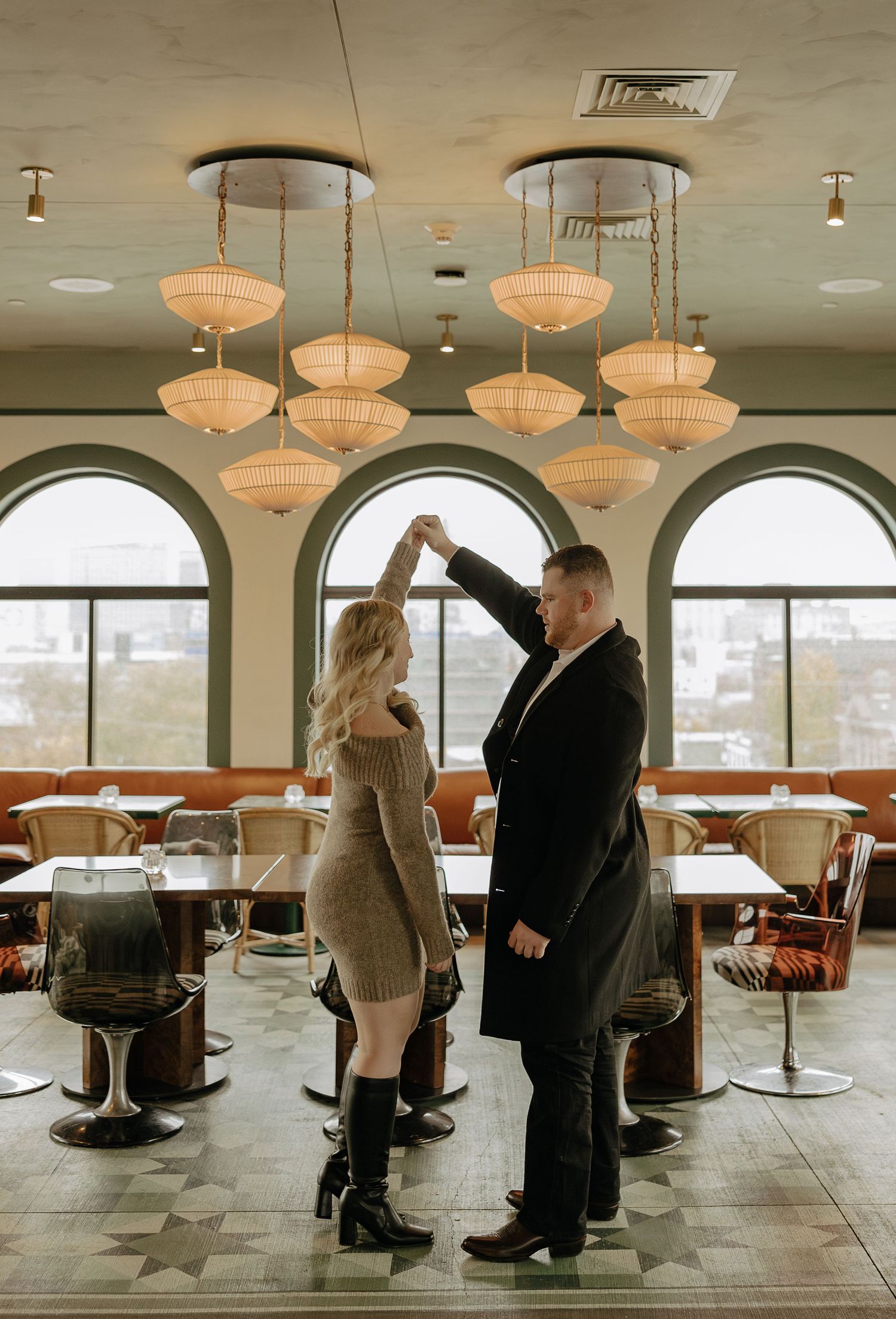 Romantic scene in an empty dining room with mid-century modern decor and large arched windows.