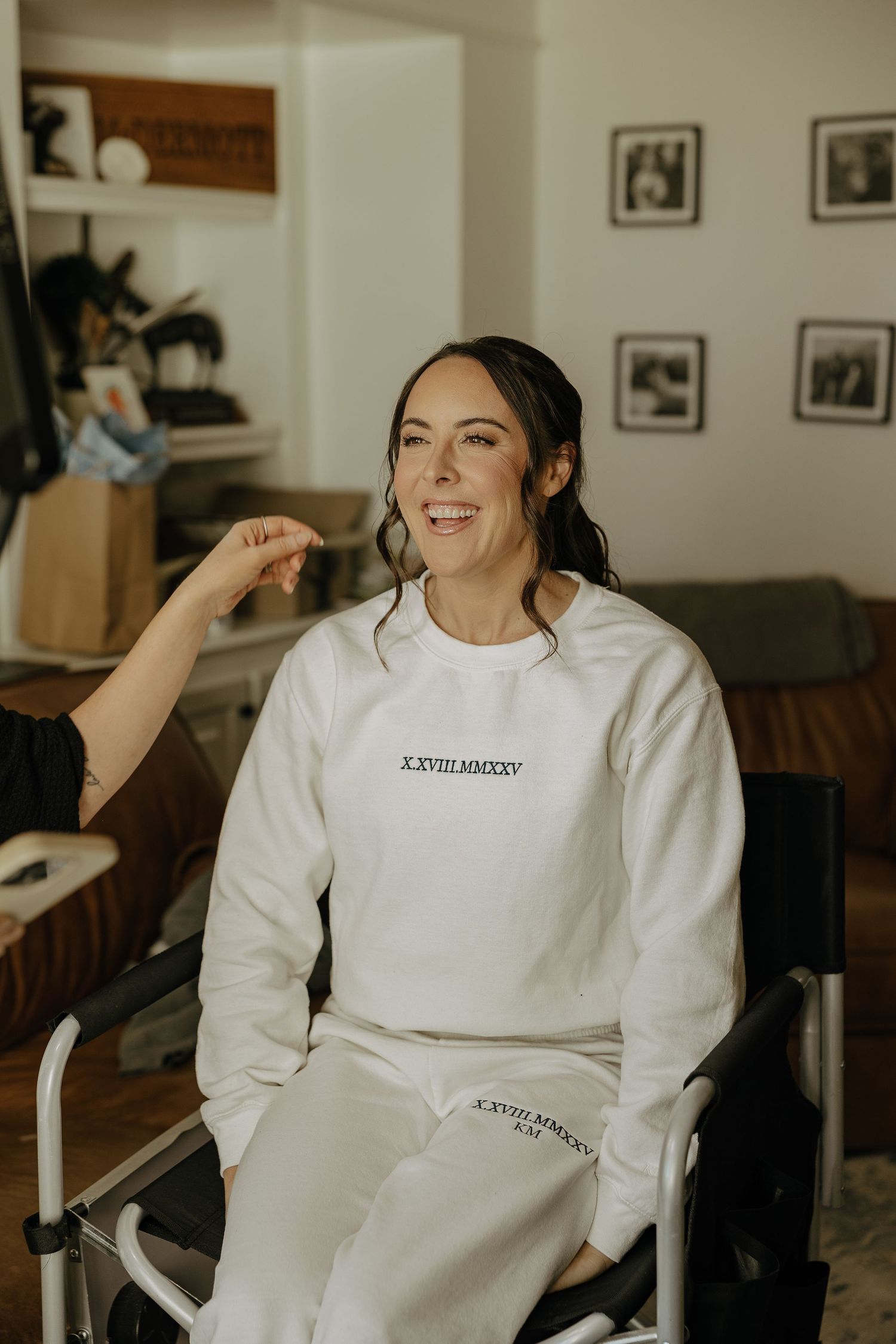 Person wearing a casual white sweatshirt with text smiling in an indoor setting.