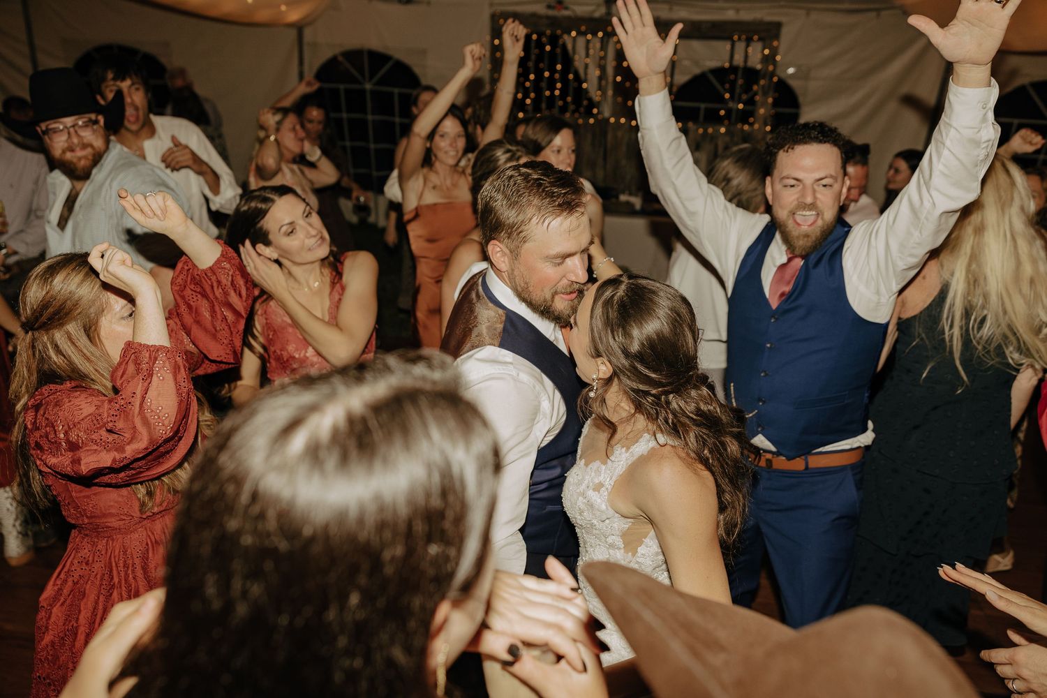 Energetic wedding reception dance party with guests celebrating on a crowded dance floor.