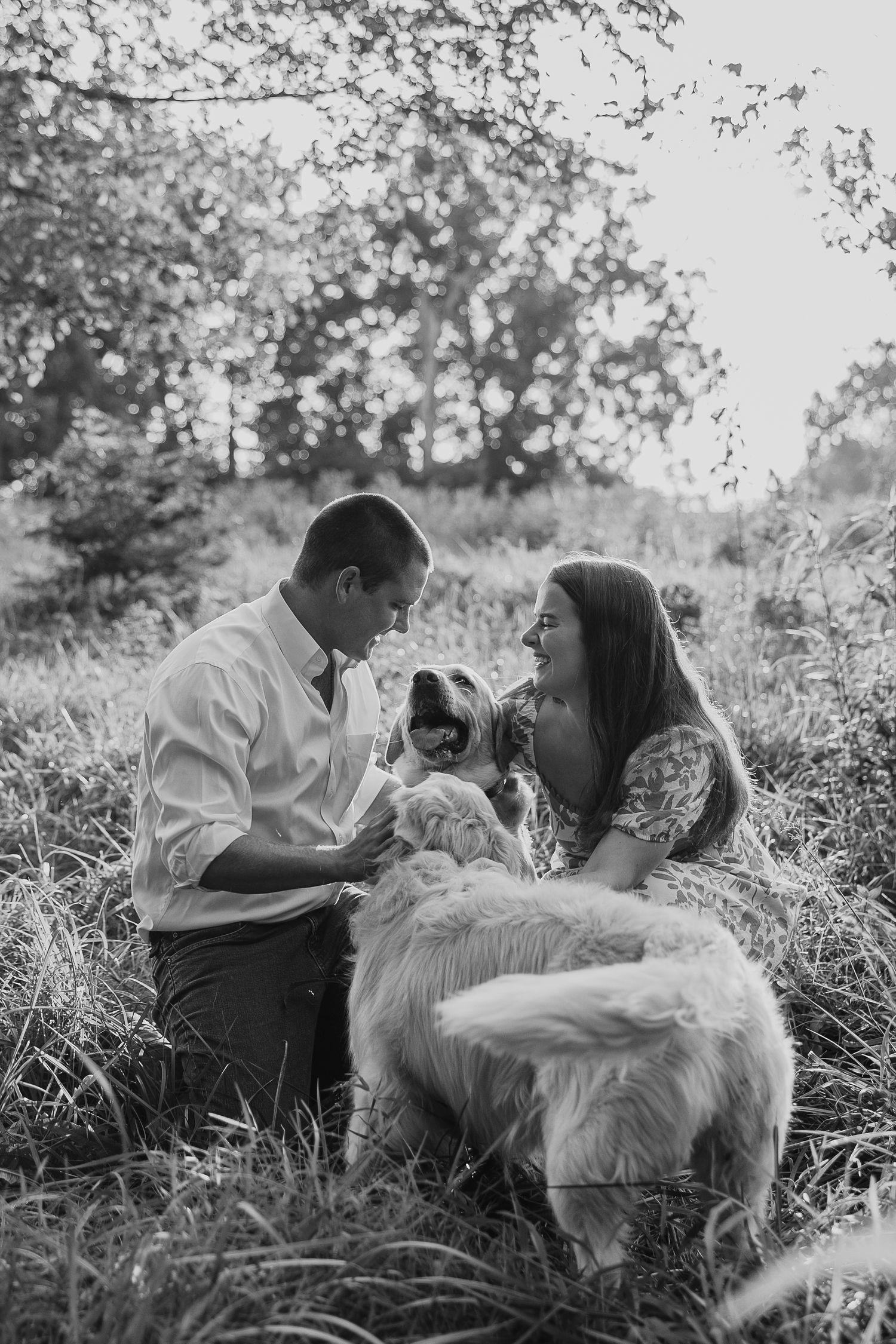 Couple relaxes in tall grass with their golden retriever during an outdoor photo session.