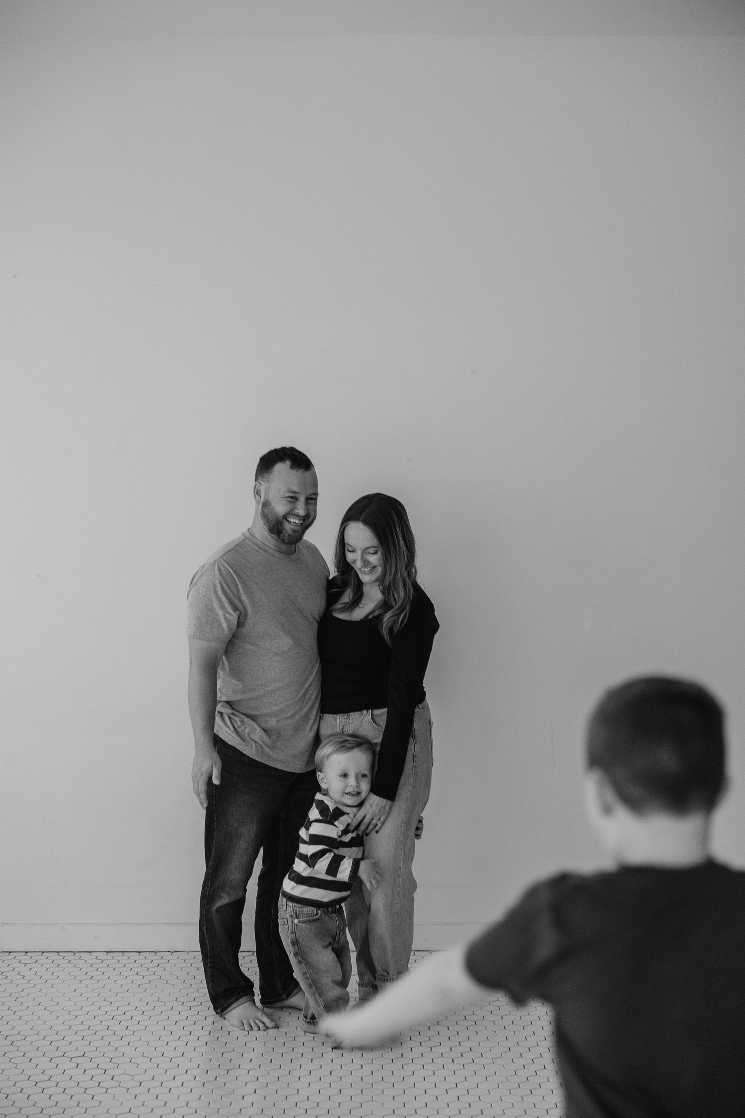 A family plays together against a minimalist grey wall background.