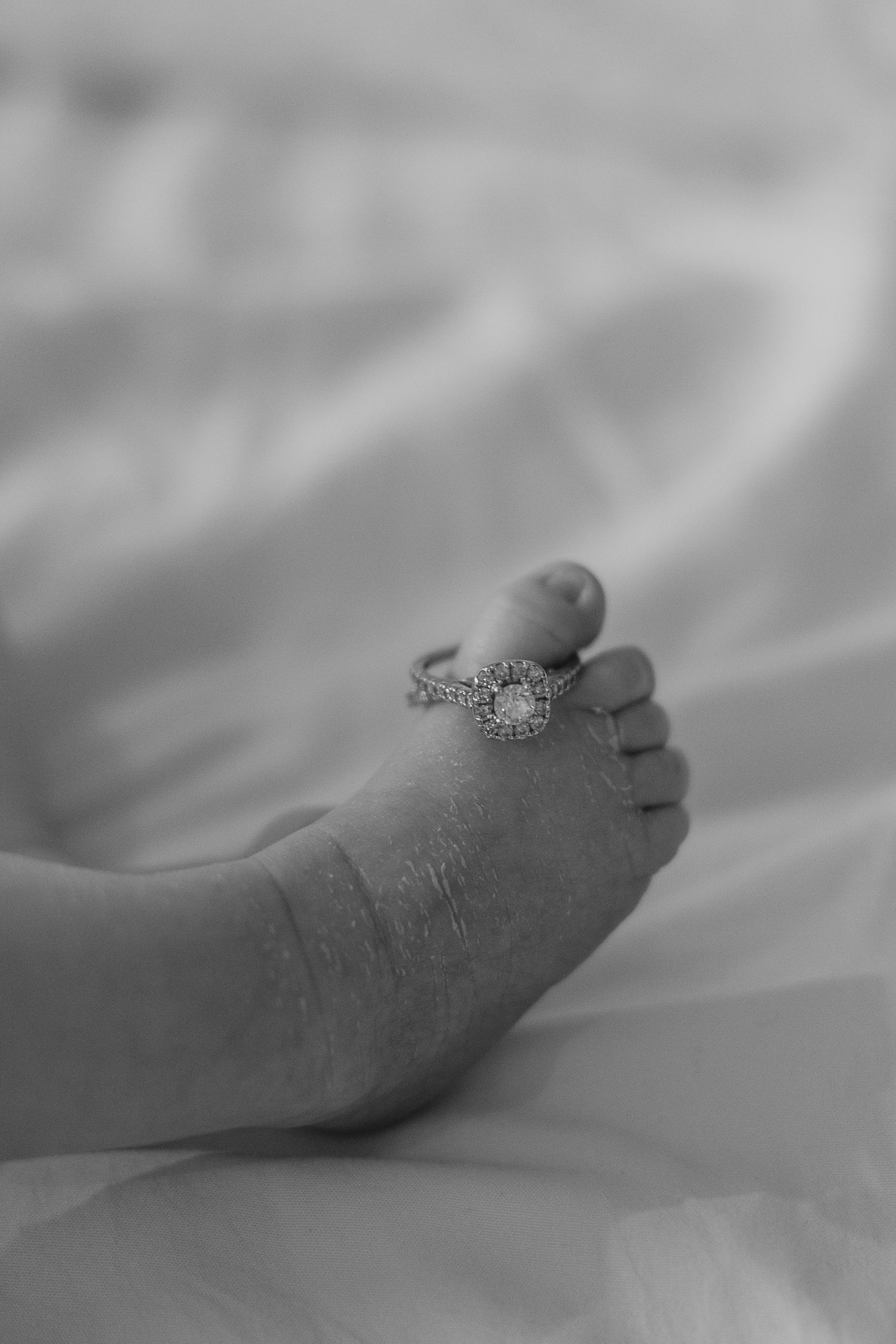 A close-up of tiny baby feet with a sparkling ring resting on top.