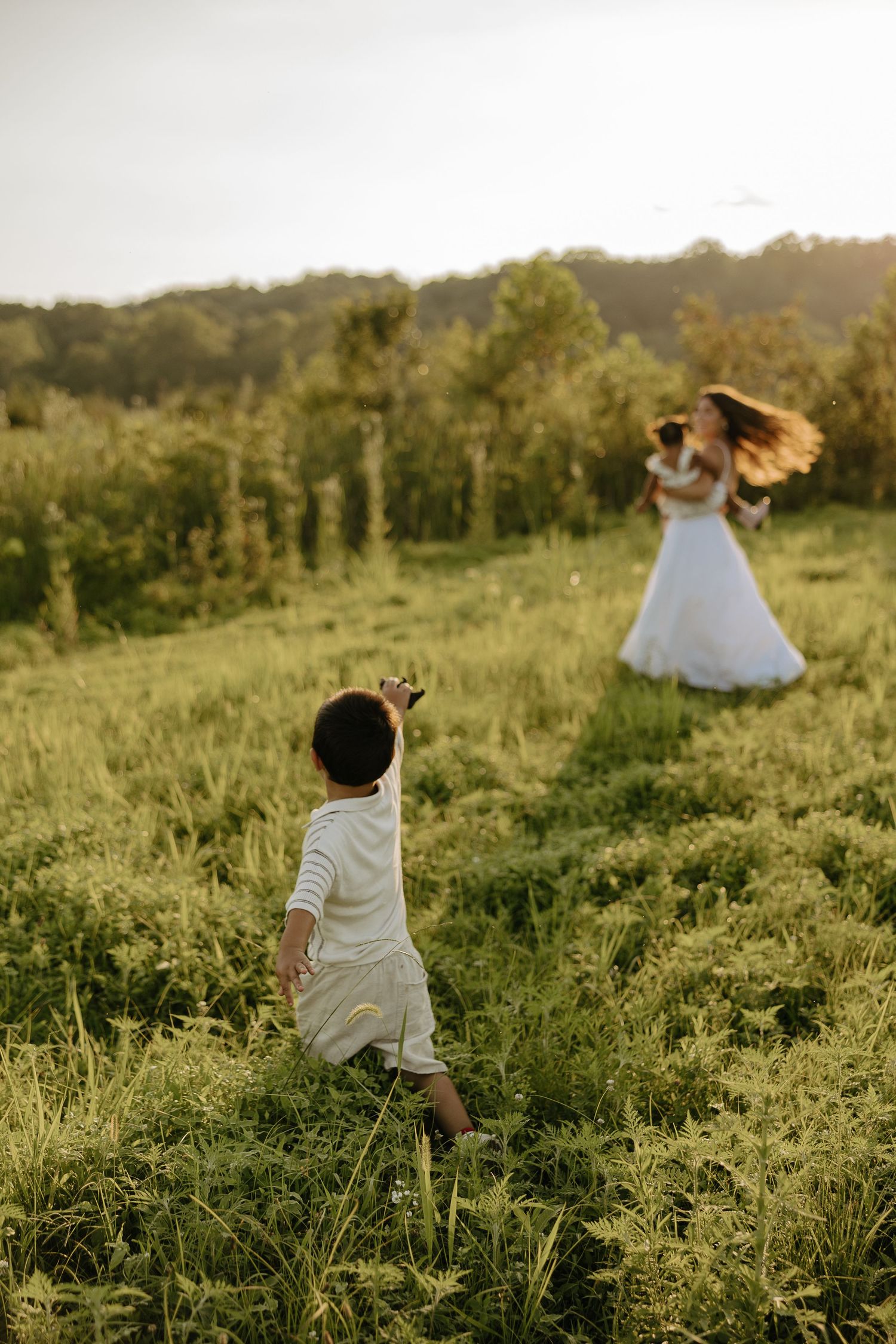 Children playing freely in tall grass during golden hour.