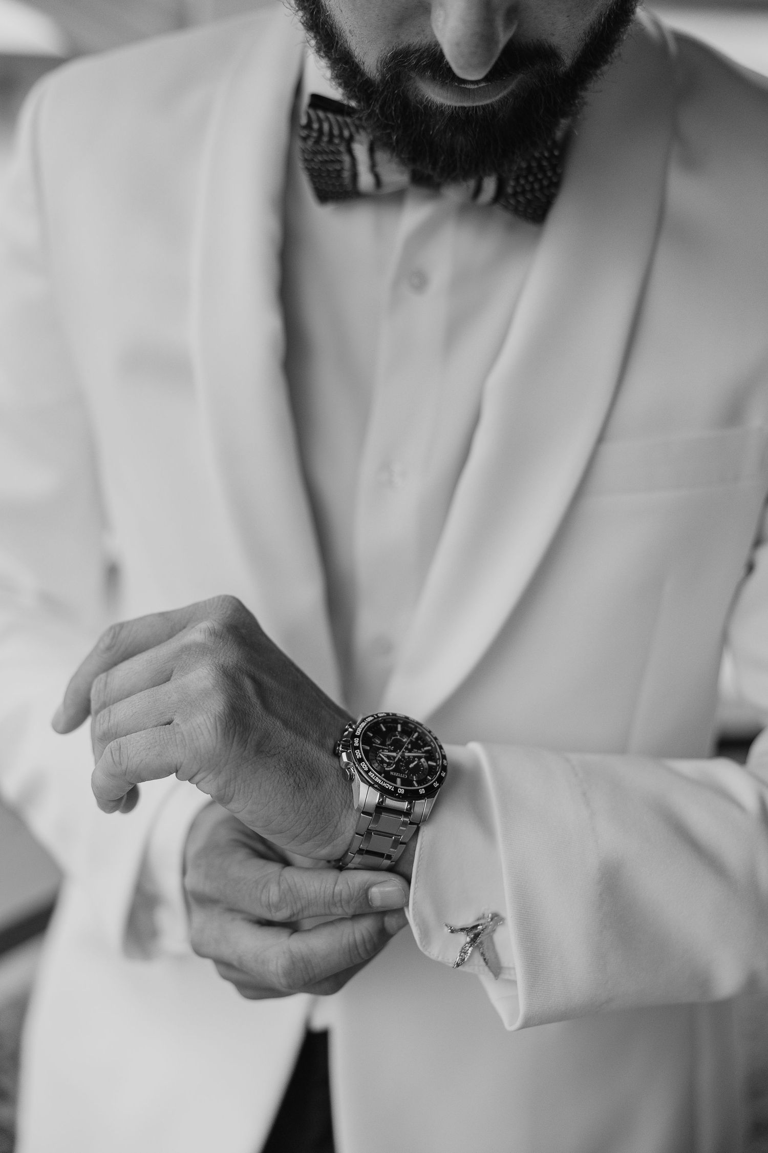 Close-up details of formal white suit and accessories in black and white.