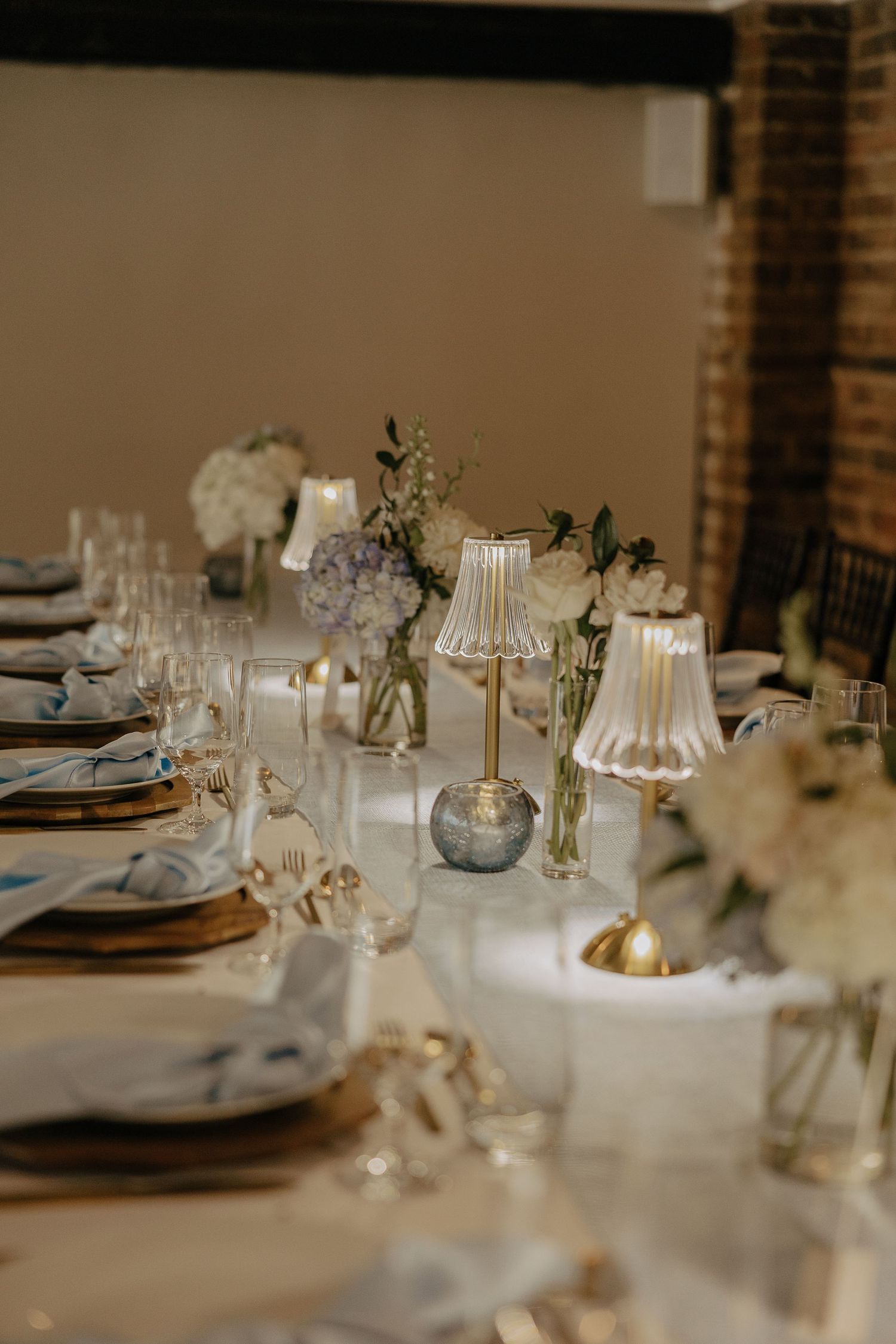 Wedding reception table settings with vintage lamps, candles and delicate place settings.