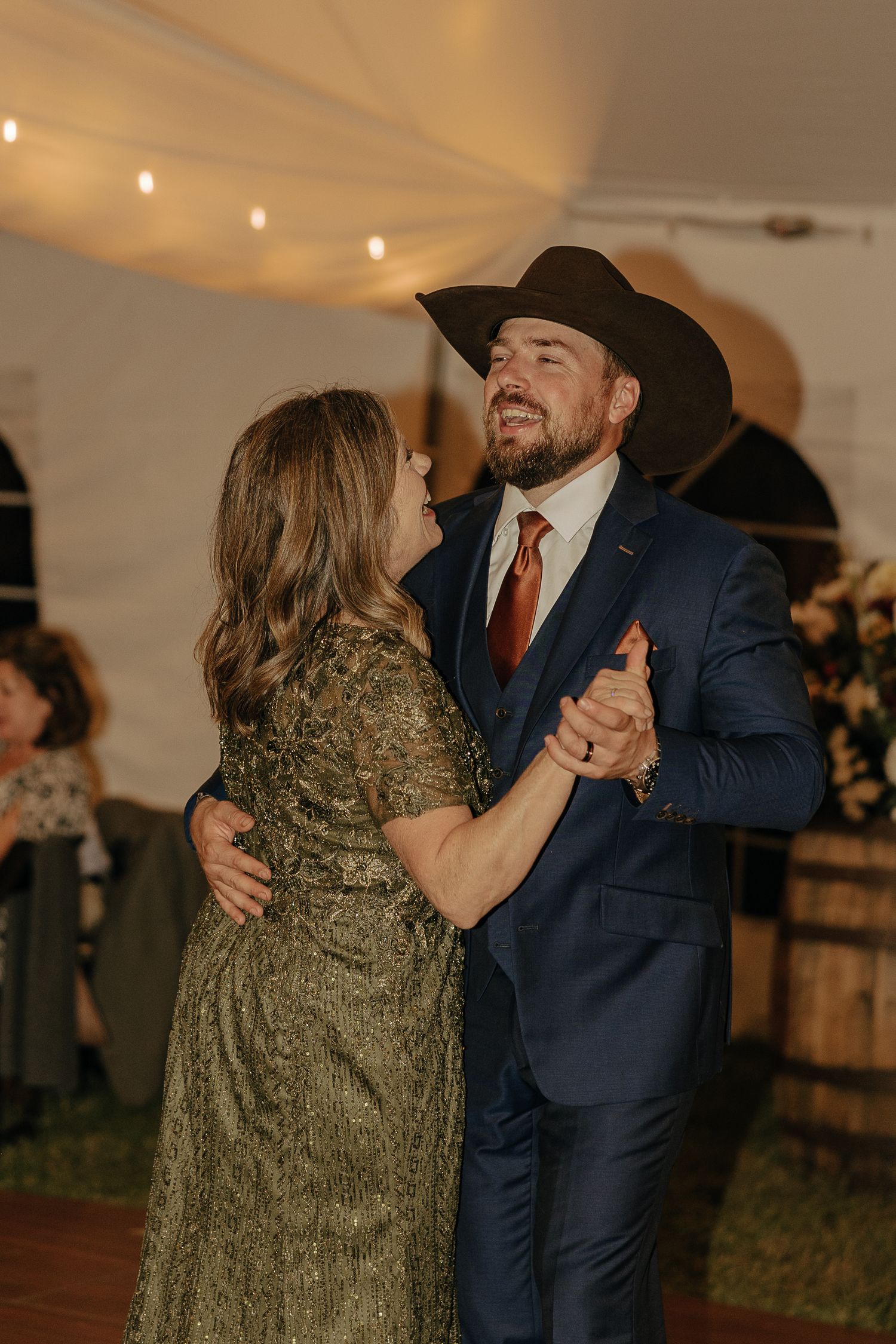 Couples dancing together at a wedding reception under warm lighting in formal attire.