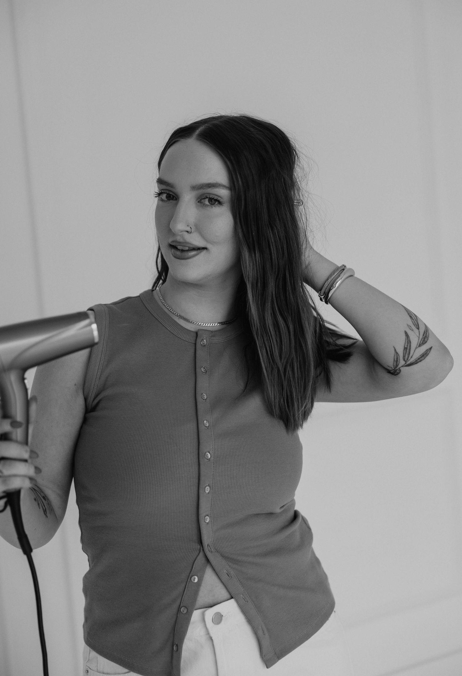 Black and white portrait showing styling pose with hair tools.
