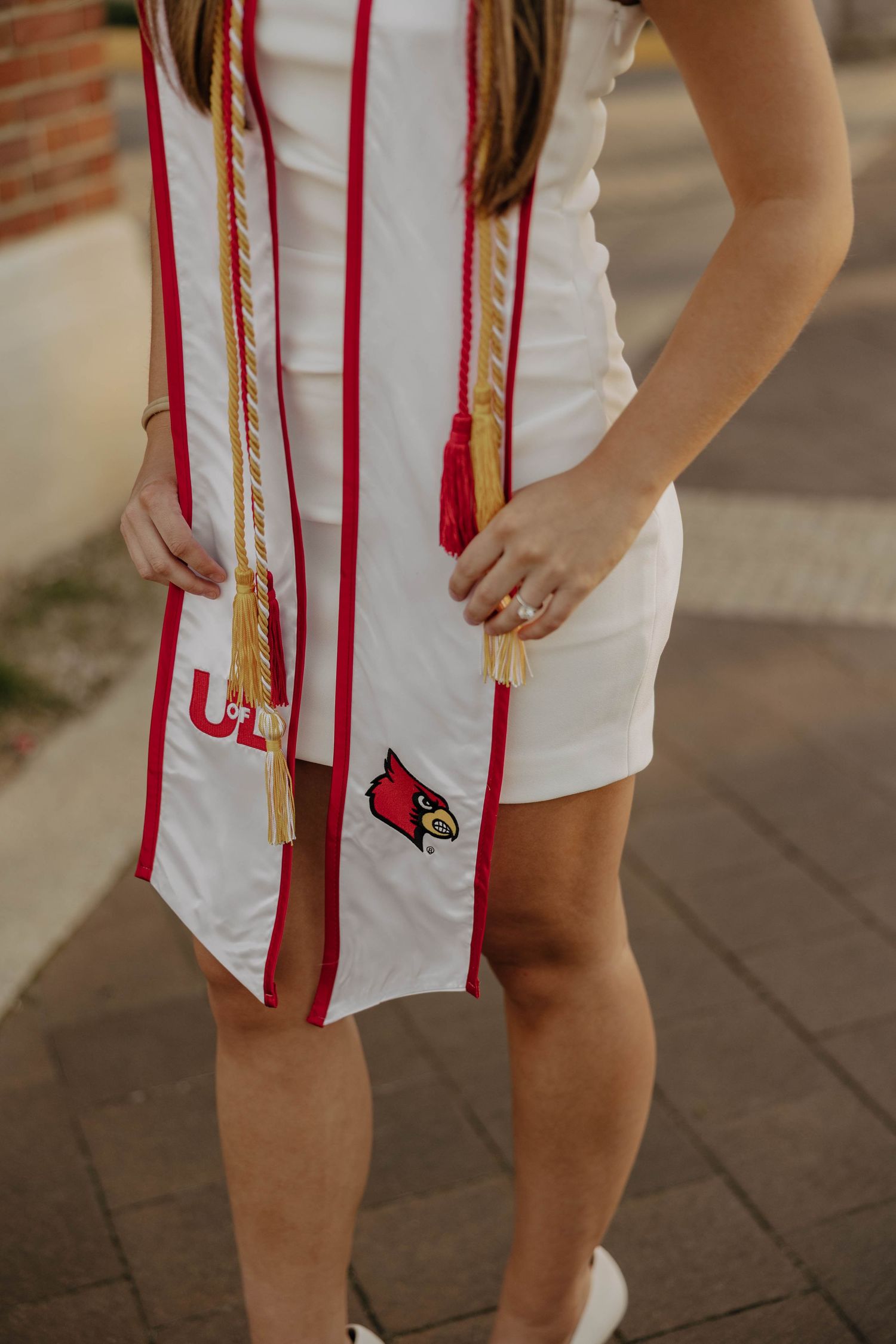 Close-up of graduation stole with red tassels and university logos.