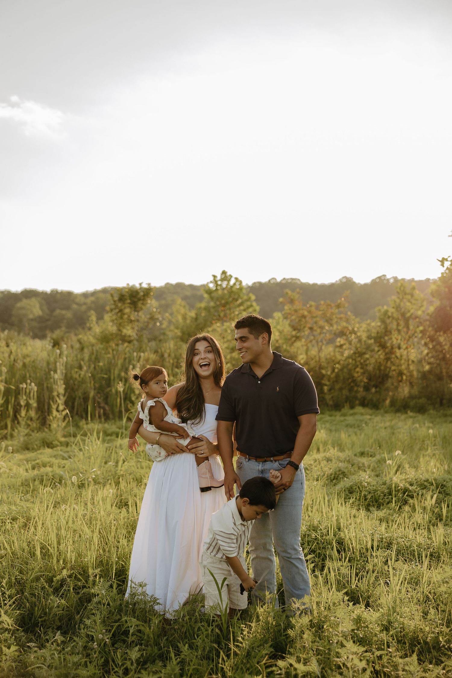 Family gathering in a serene meadow during sunset photography session.