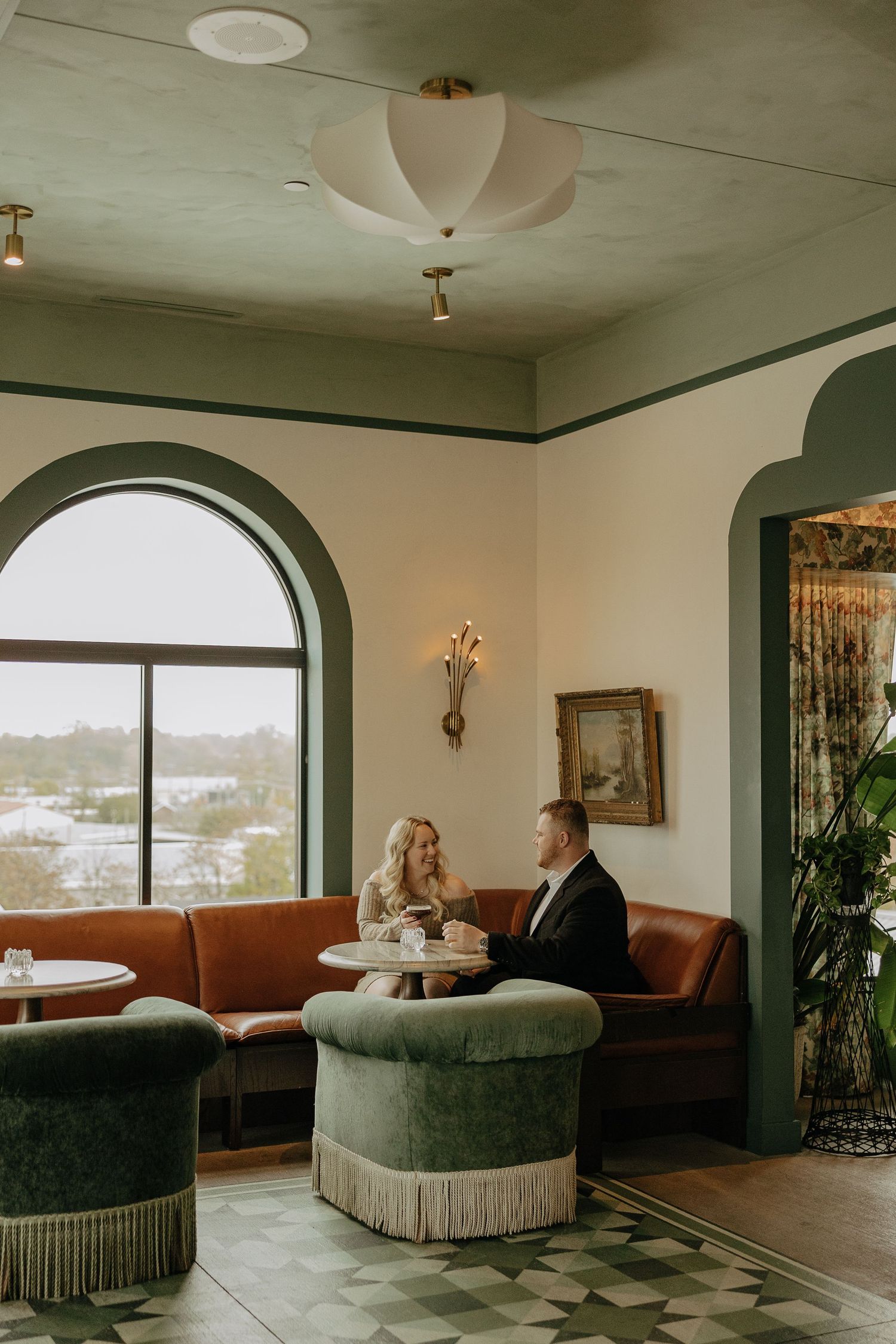 Panoramic view of a luxurious lounge area with curved walls, plush seating, and arched windows overlooking a cityscape.