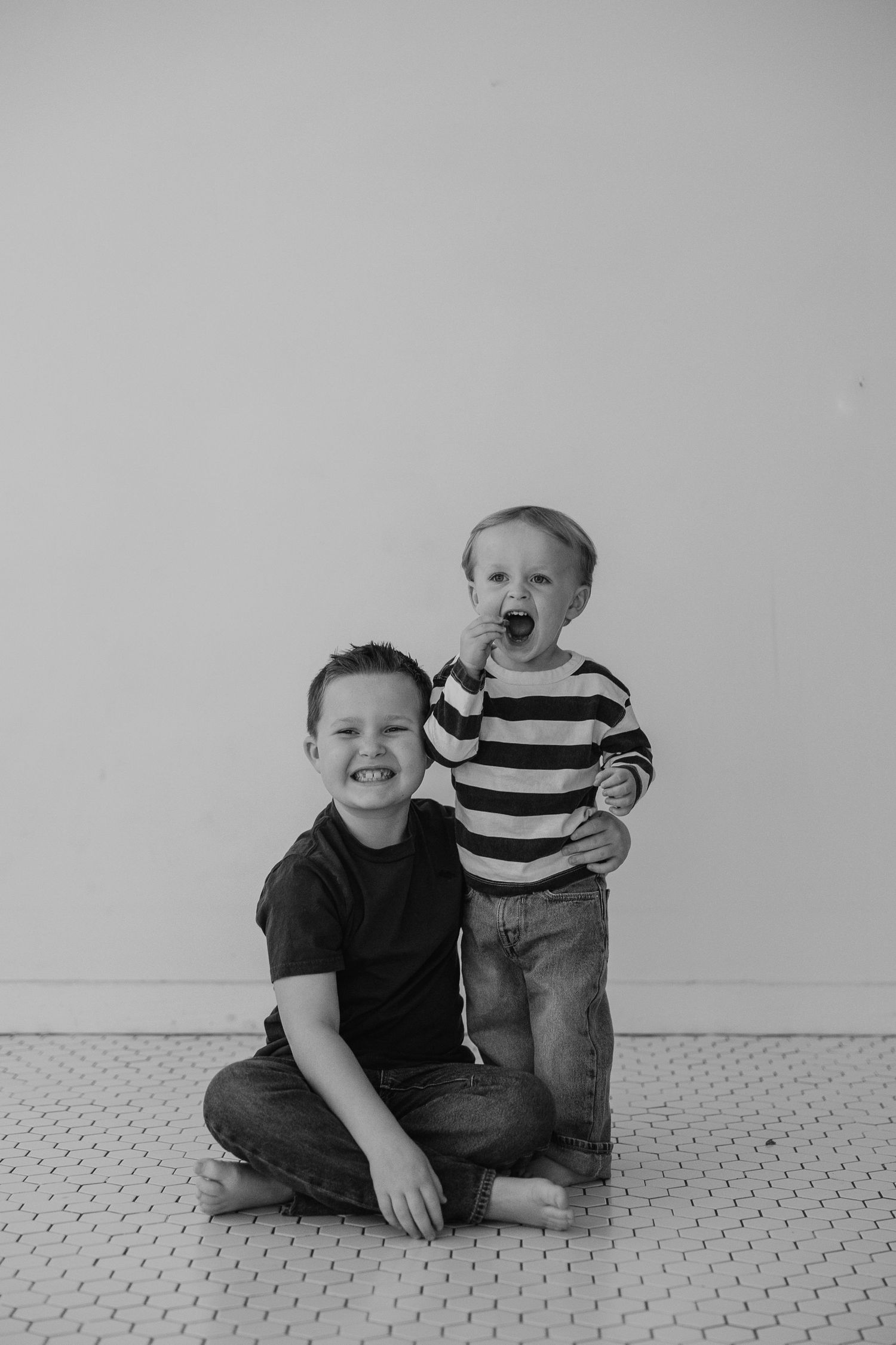 Black and white photo series showing joyful interaction between two people on a carpeted floor.