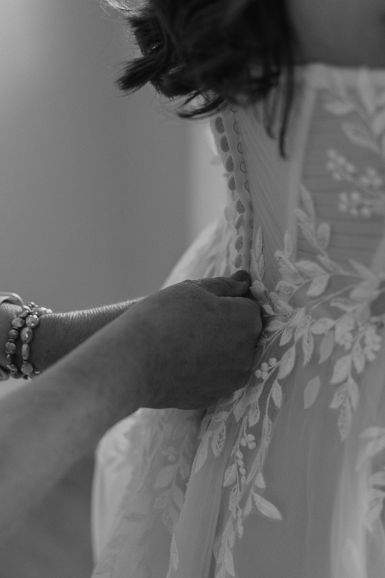 Close-up detail shot of delicate lace embroidery on a white wedding dress.