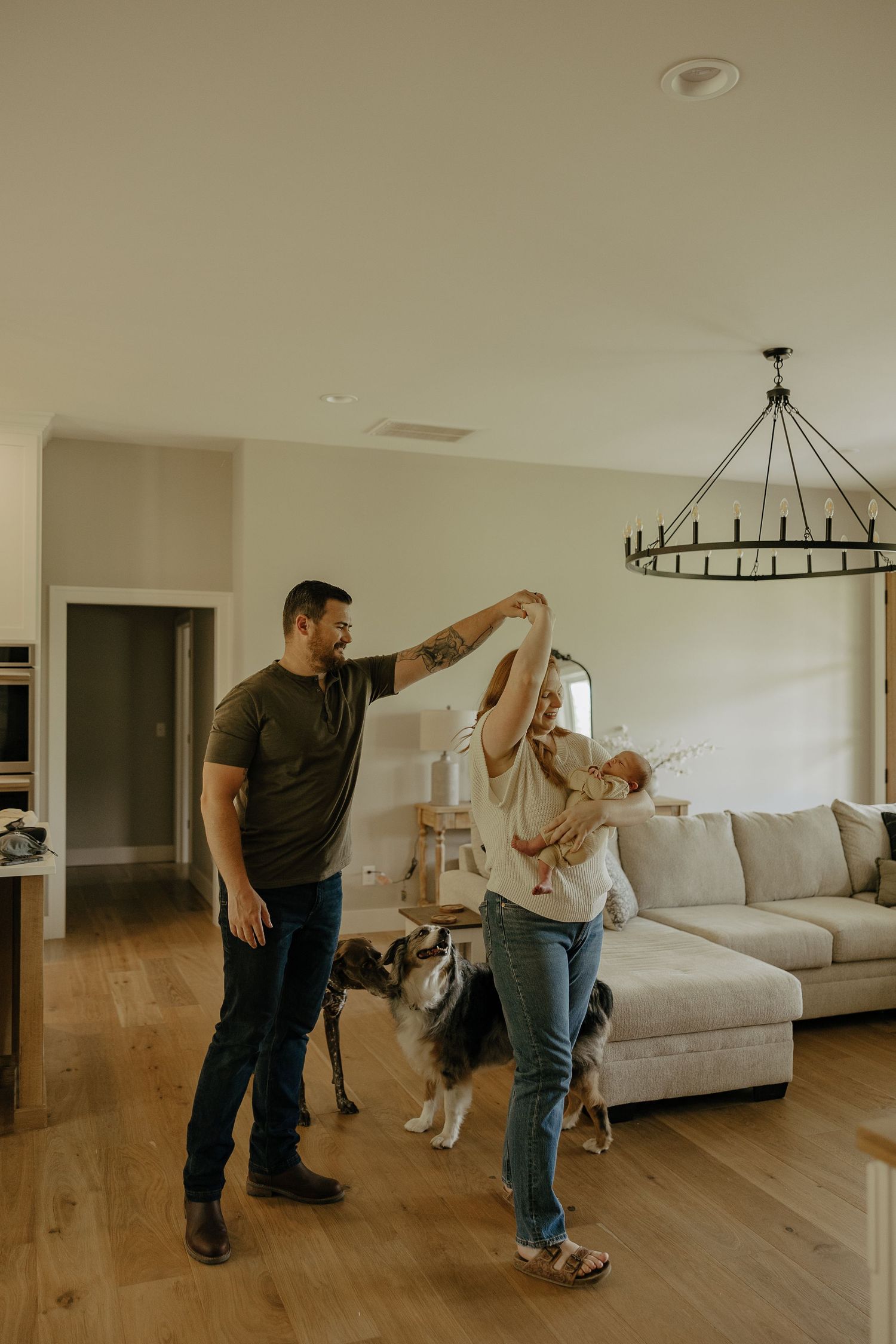 A couple dances playfully in their living room with a dog watching nearby.