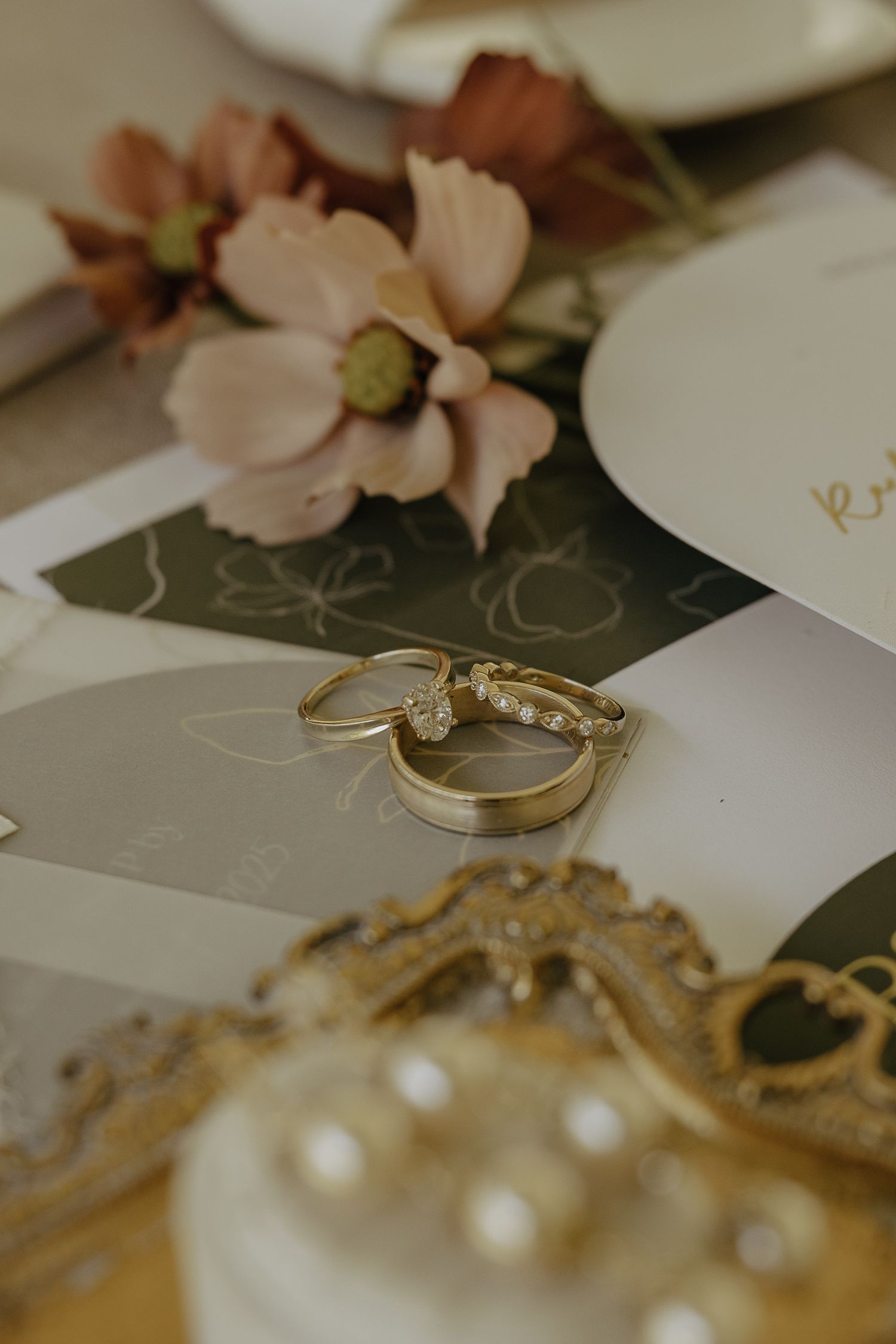 Gold wedding rings and delicate floral details displayed on elegant white paper.