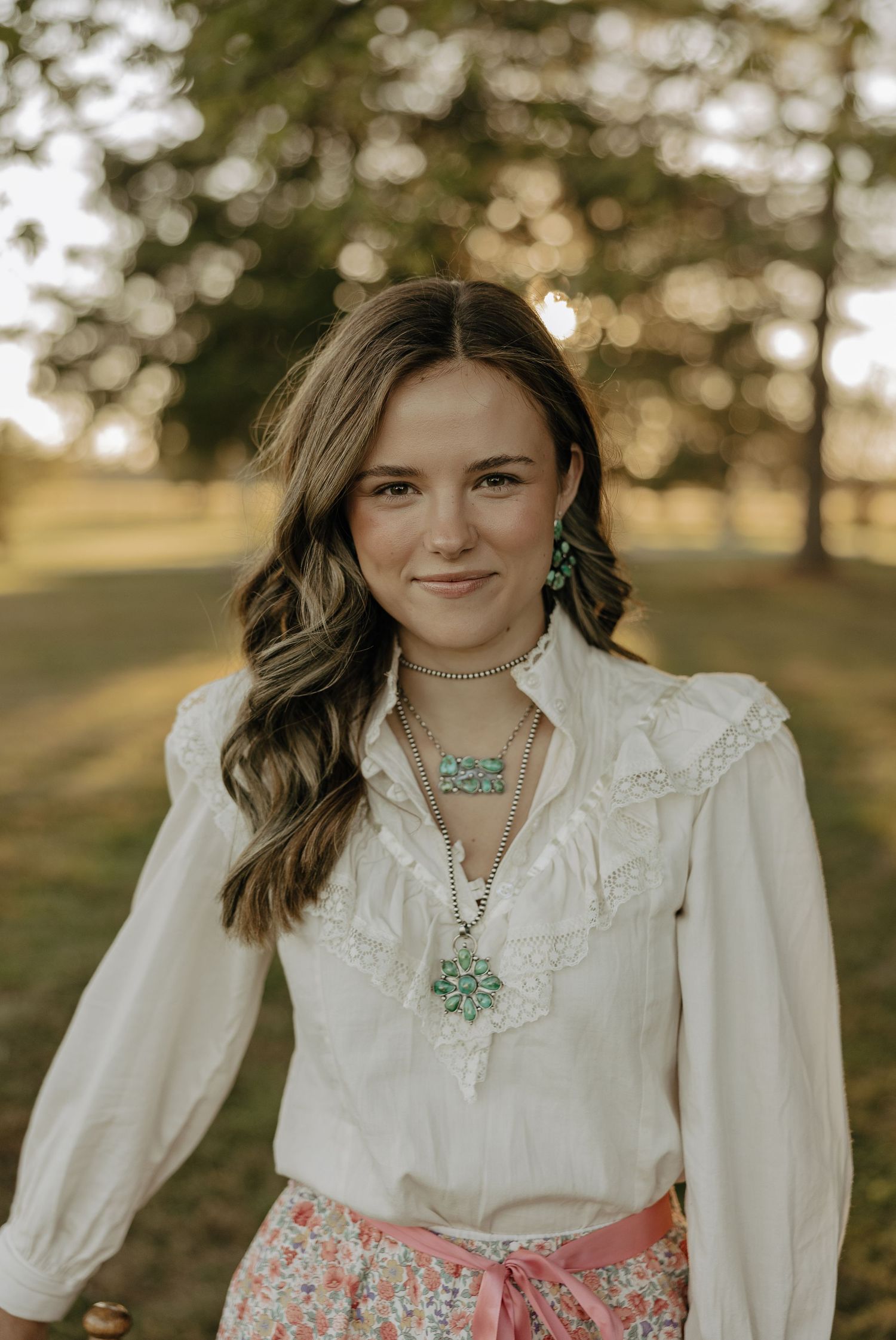 A white blouse with pink skirt ensemble styled with turquoise jewelry in outdoor lighting.