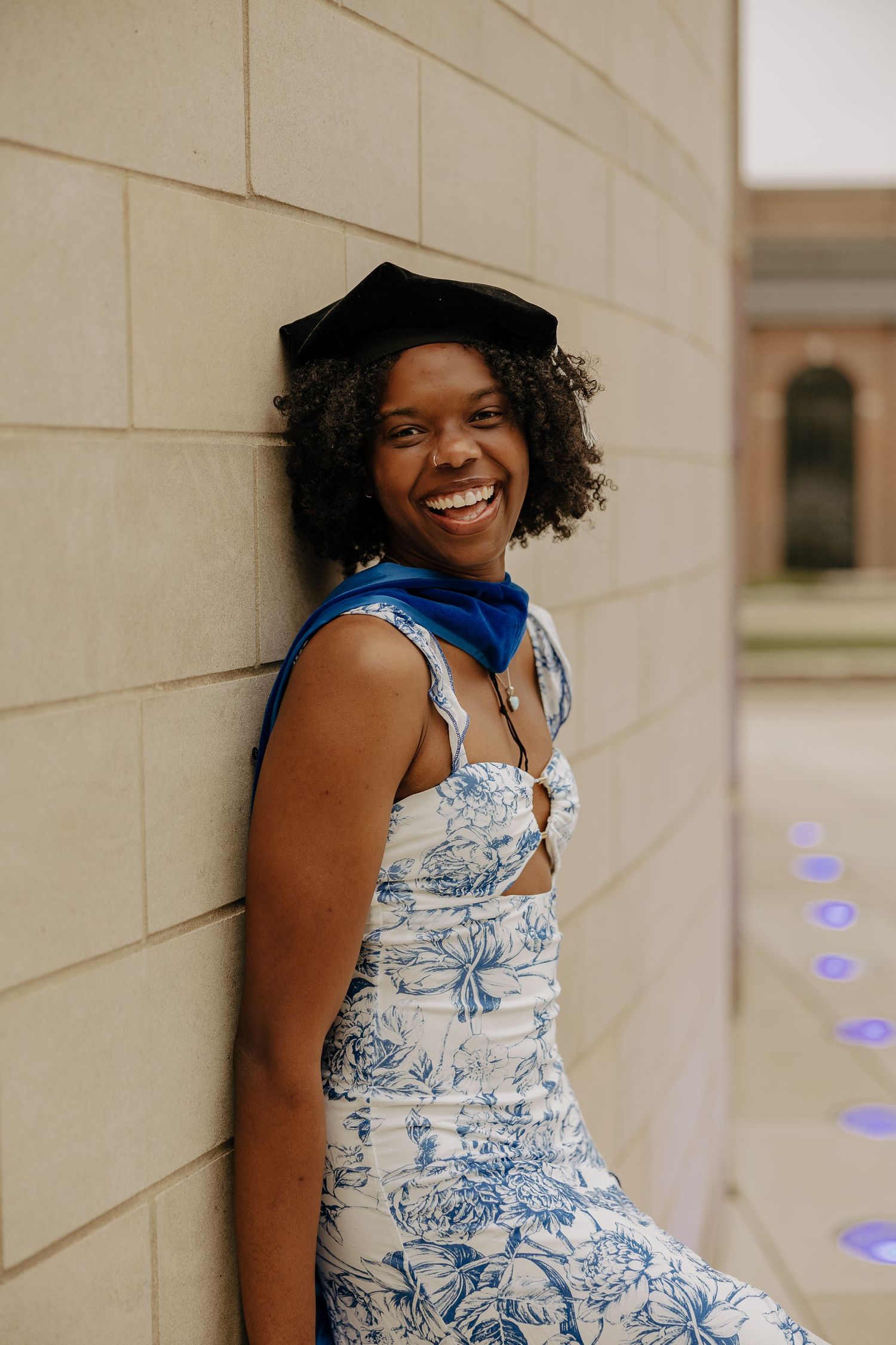 Elegant graduation portraits featuring blue and white floral dress against neutral backdrop.