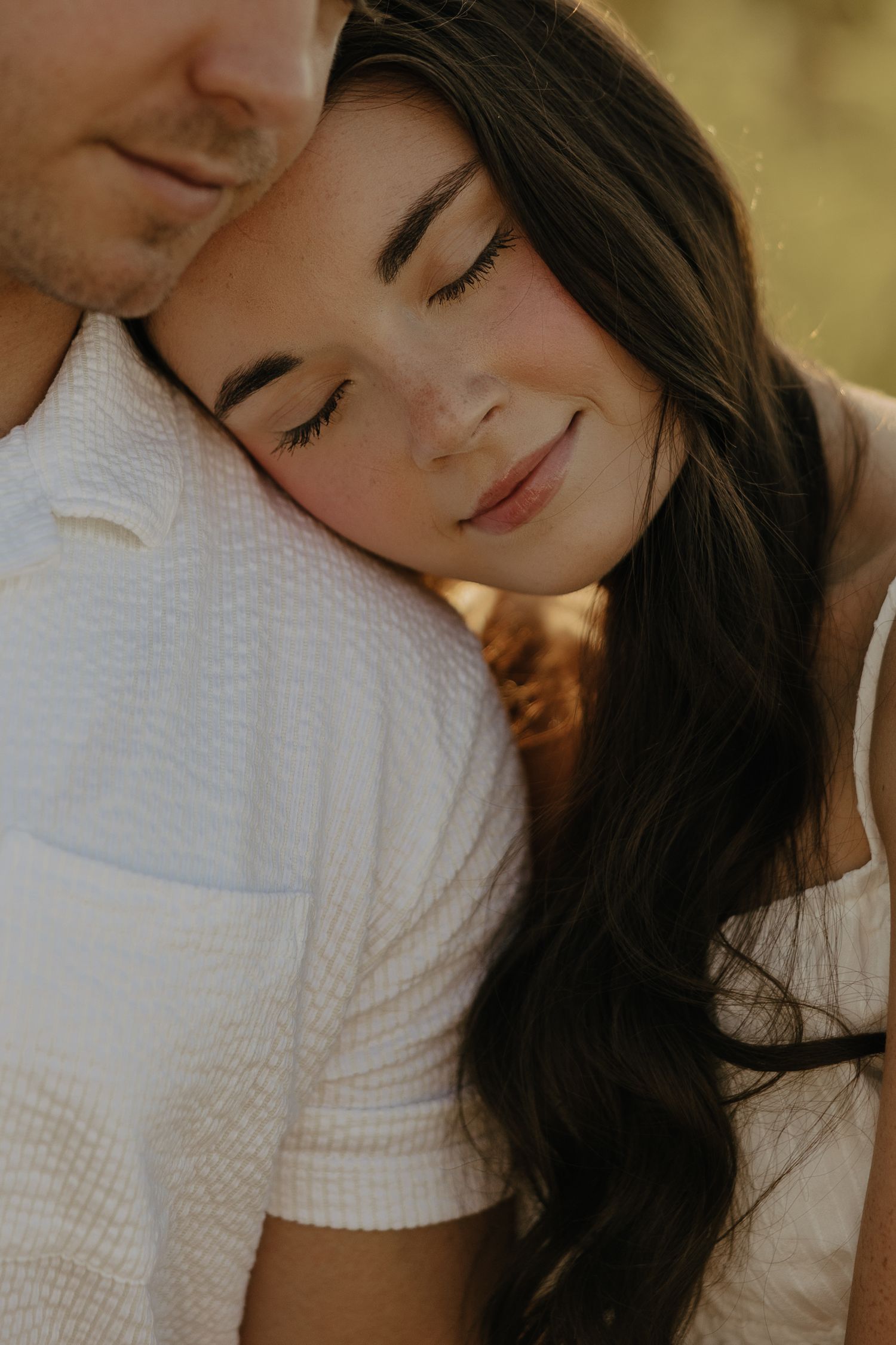 Intimate close-up portrait showing tender romantic moment in warm sunlight.