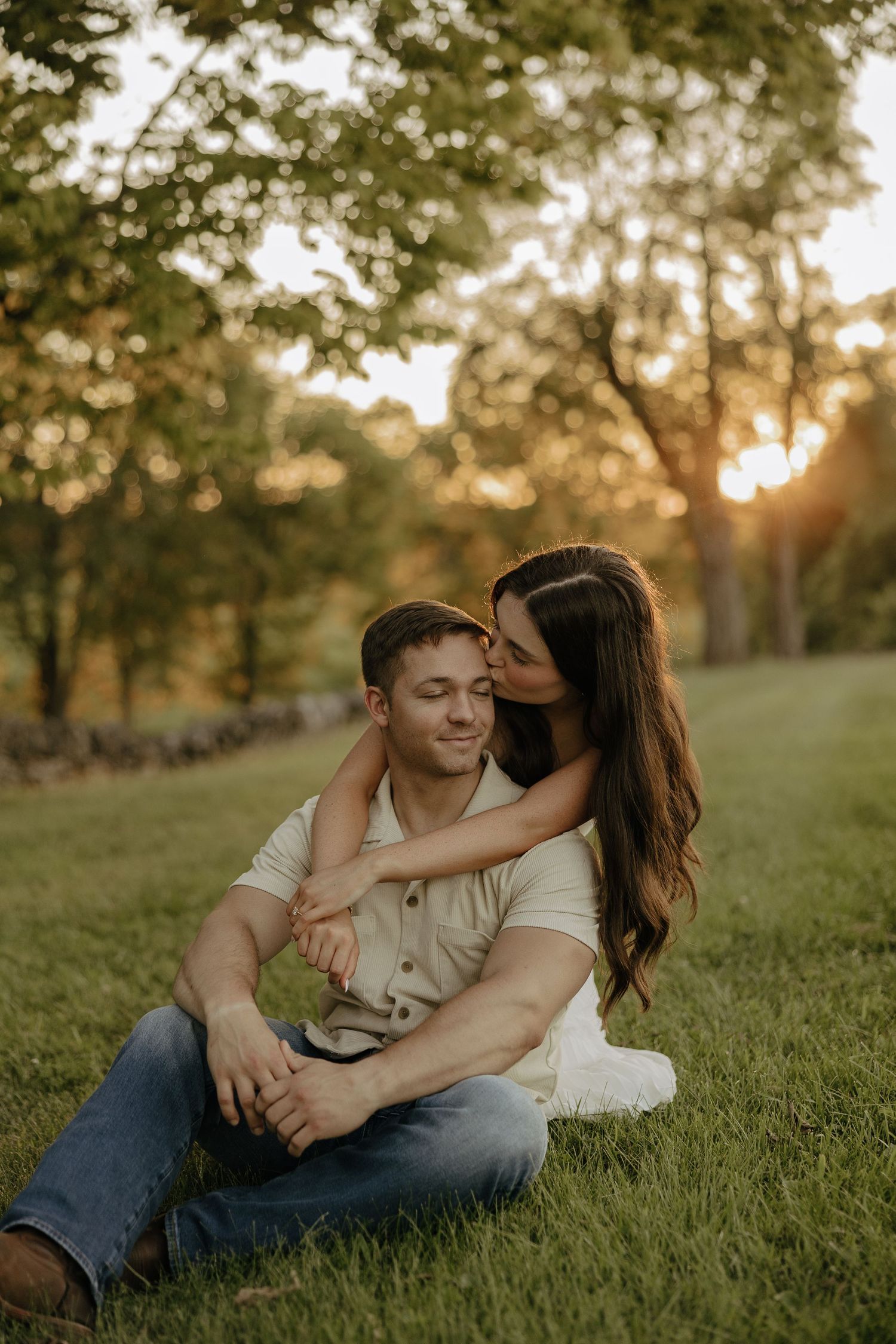 A couple shares intimate moments while lounging in grass during golden hour.