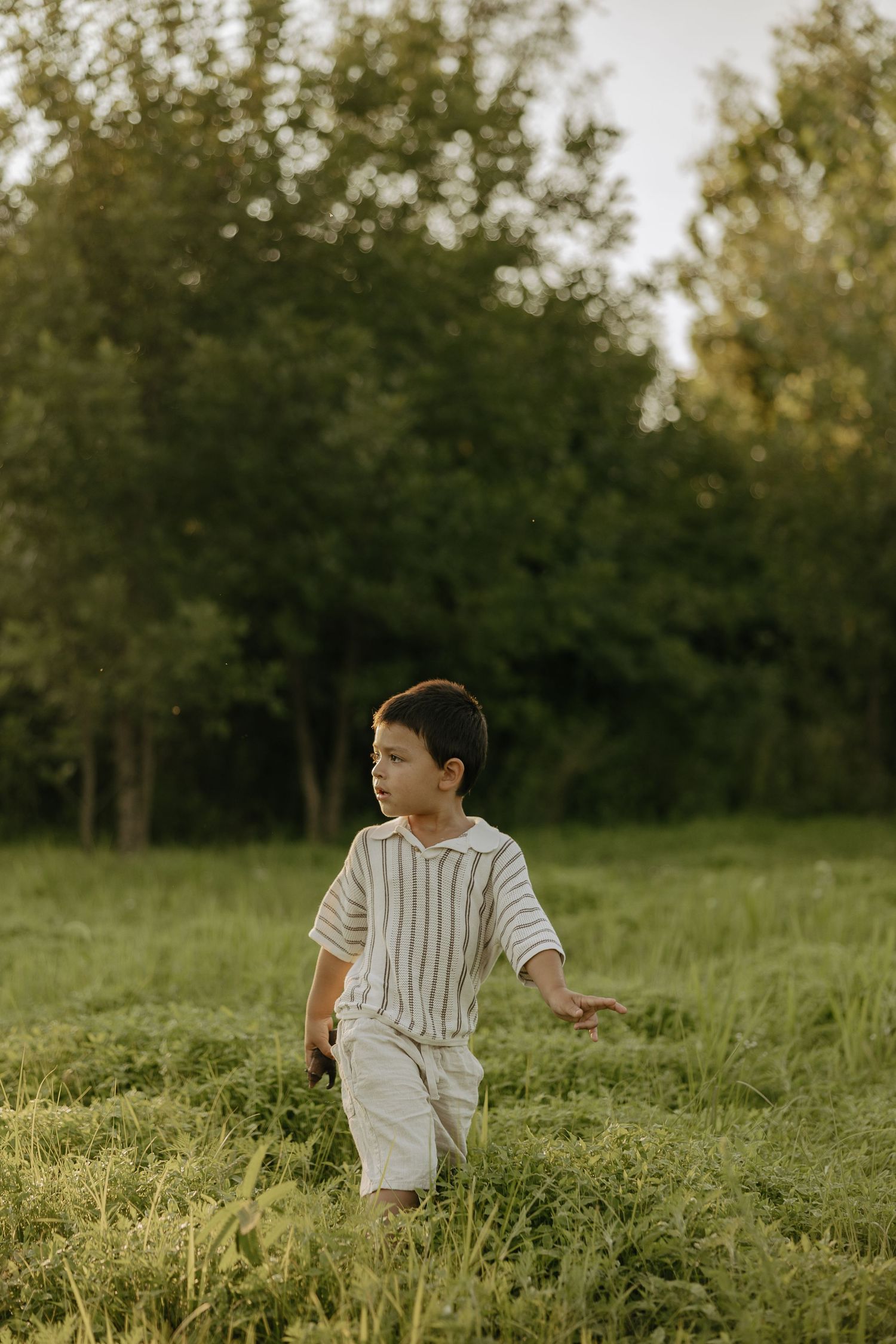 Children running and playing in a lush green meadow at sunset.