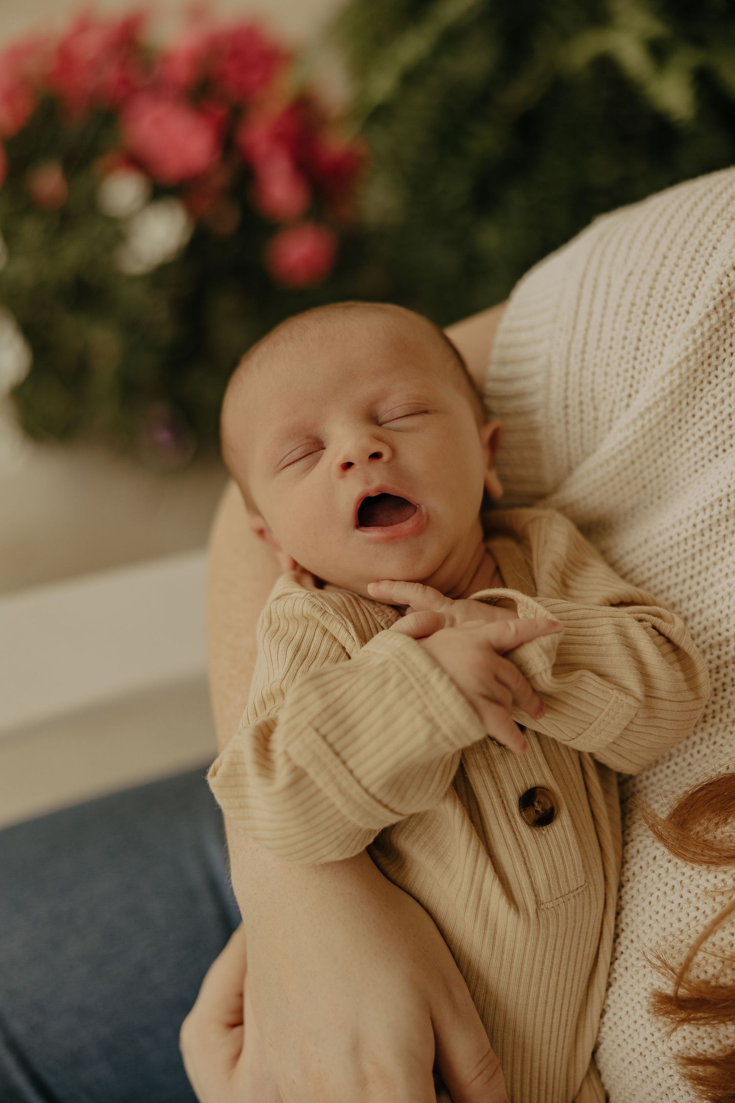 A sleeping newborn baby wearing a cream-colored bow outfit rests peacefully.