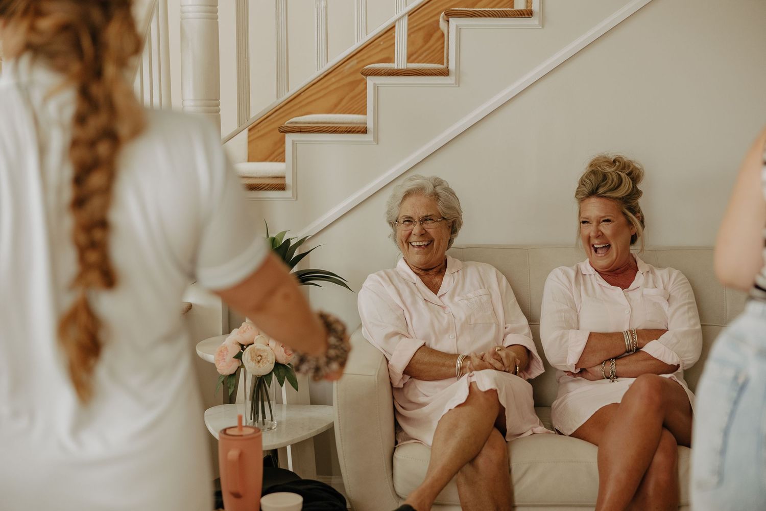 Getting ready candid moments during wedding preparations with white robes and natural lighting.
