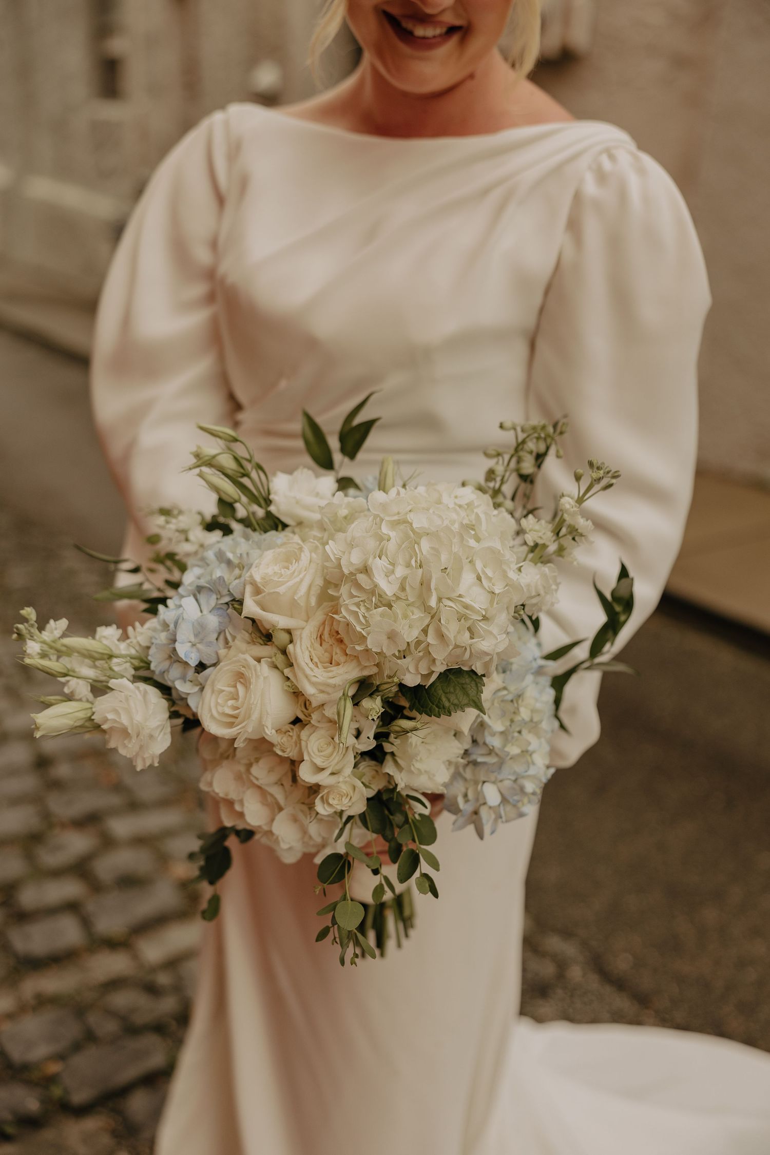 Elegant white and pale blue floral wedding bouquet with roses and delicate greenery.