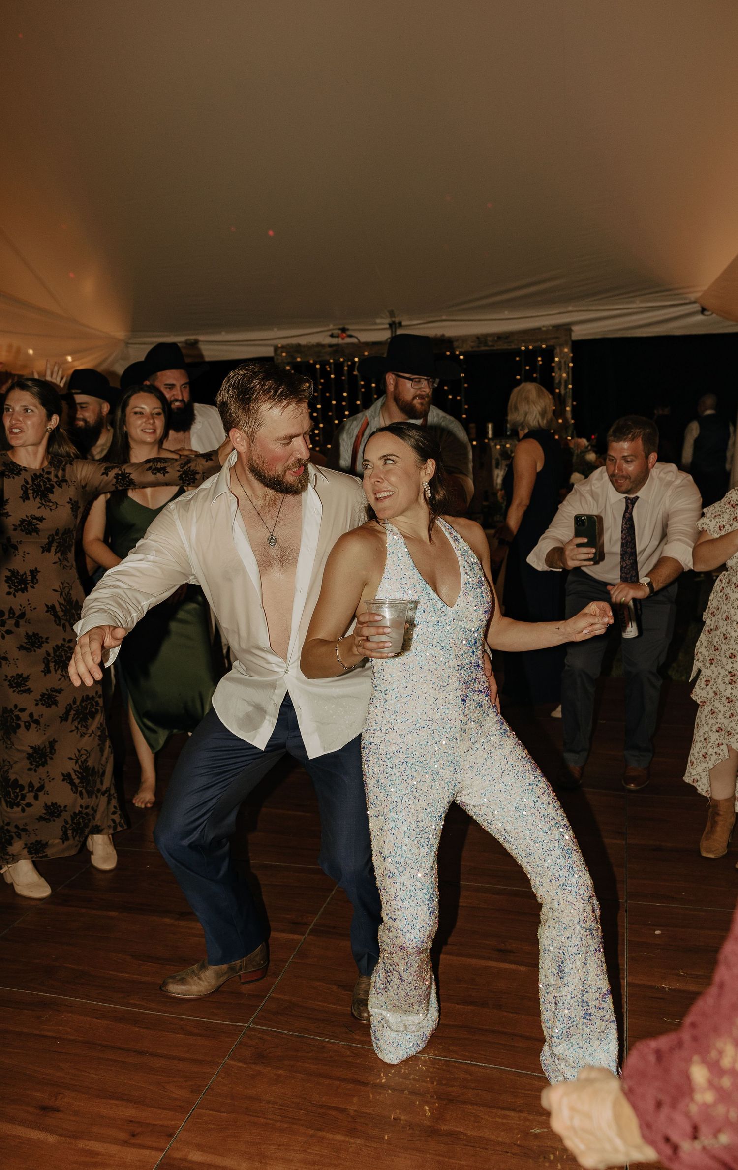 Couple dancing at their reception, bride wearing a sparkly jumpsuit.