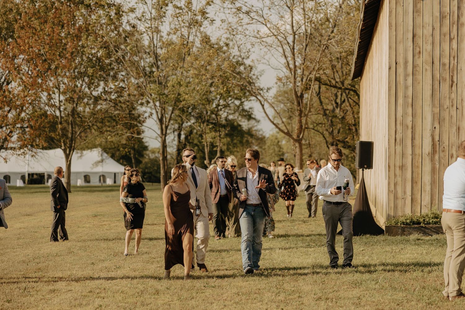 Outdoor gathering of people near rustic wooden structures in autumn setting.
