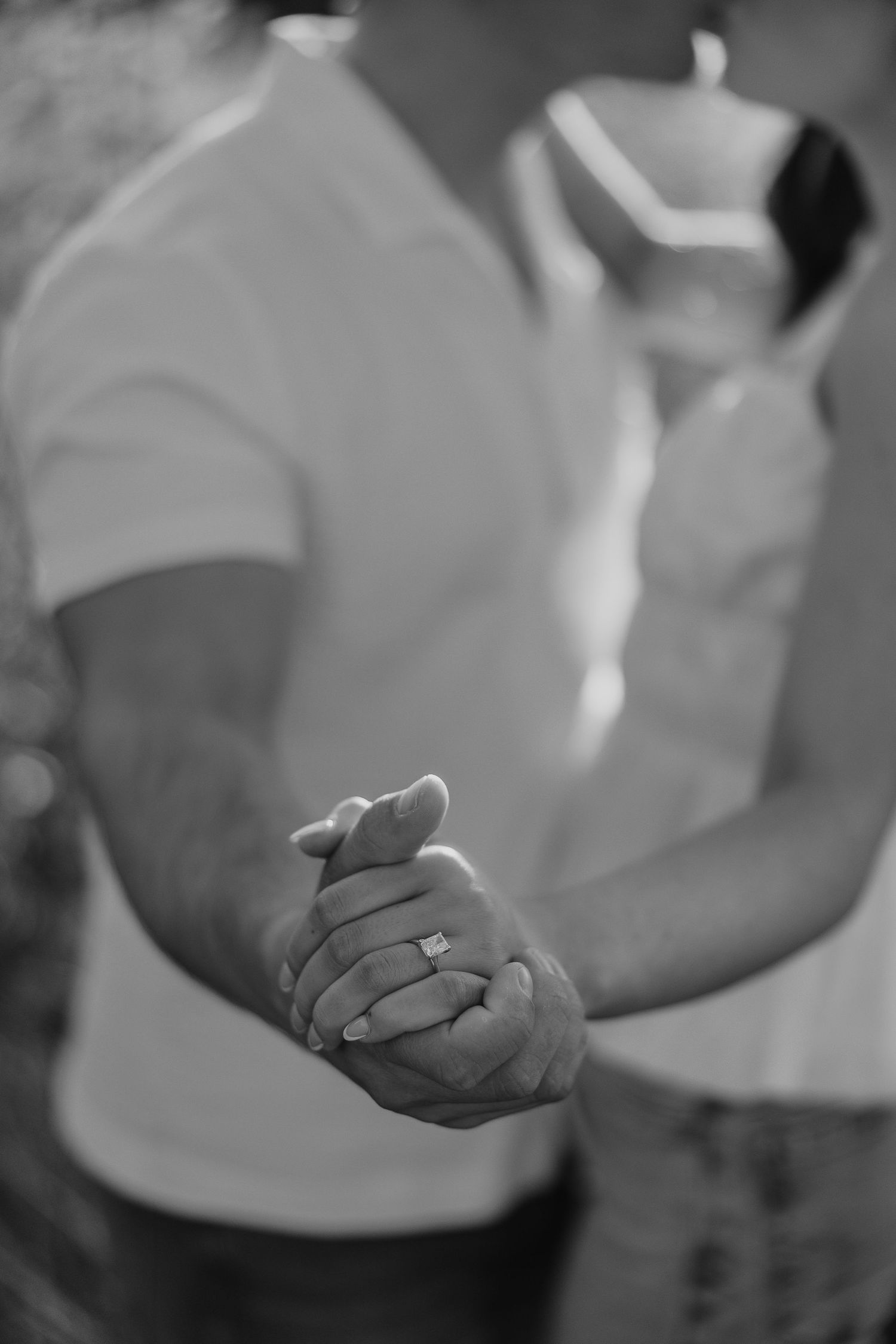 Black and white close-up showing engagement ring detail.