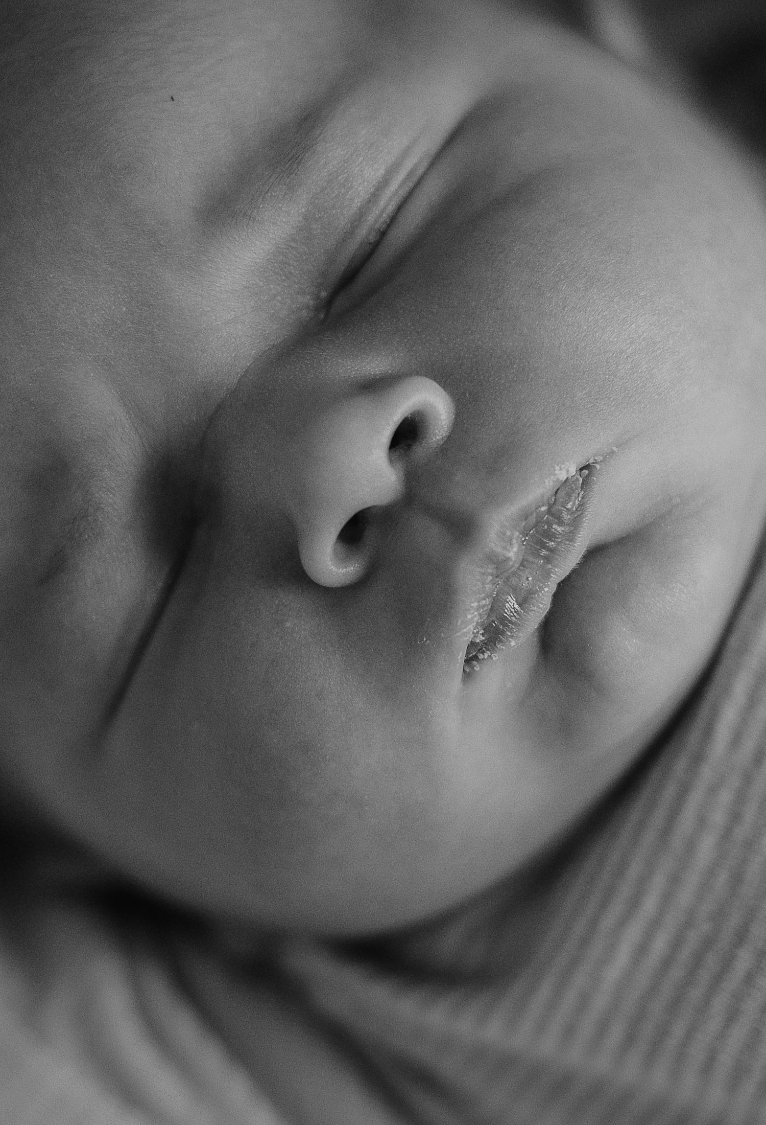 Intimate black and white macro shot of a sleeping infant's features.