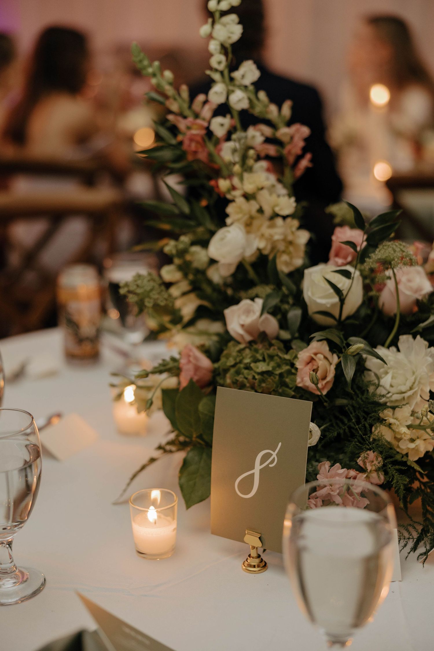 Elegant wedding reception table with white floral centerpieces and glowing candlelight.