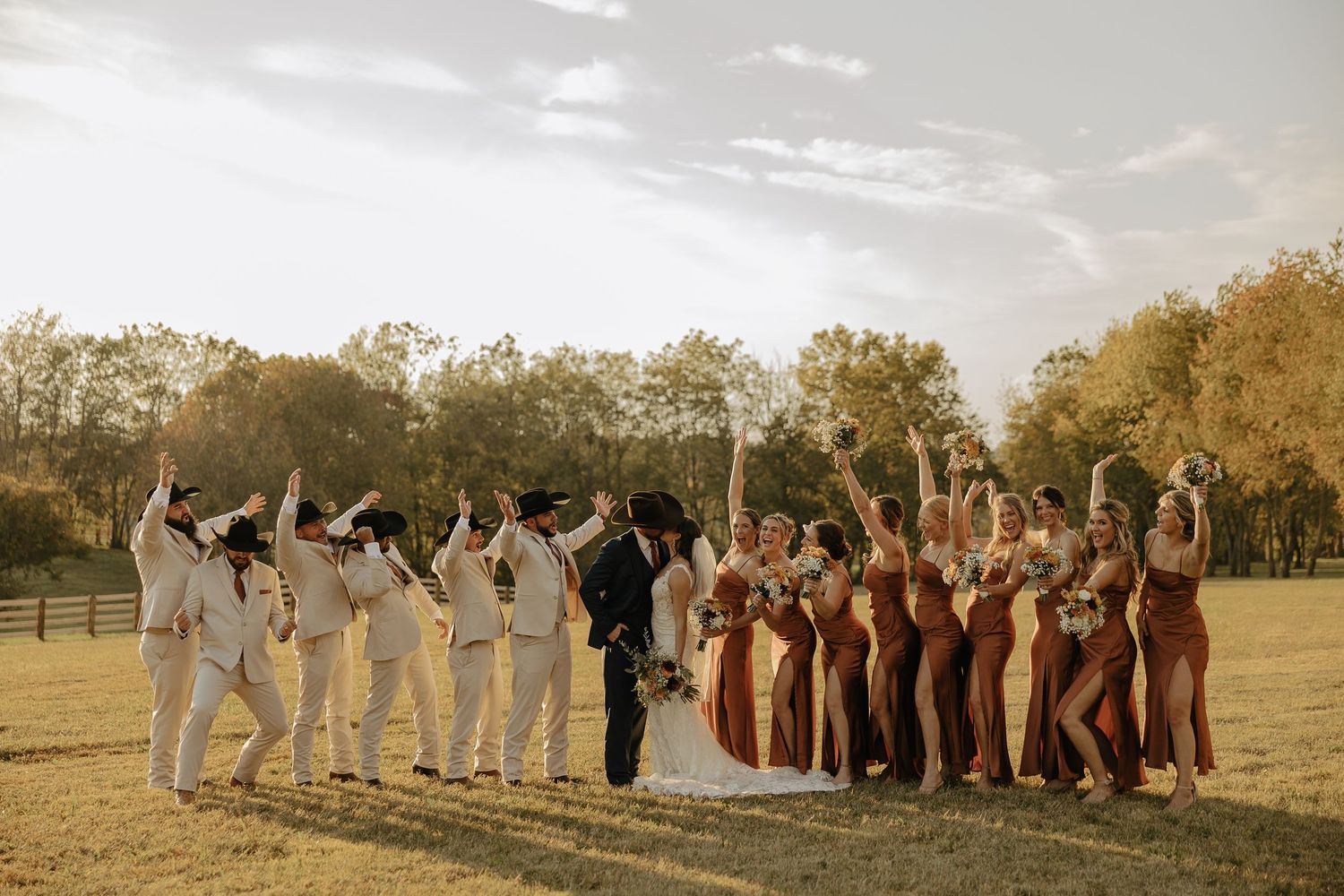 Wedding party posed in a panoramic shot across an autumn field.