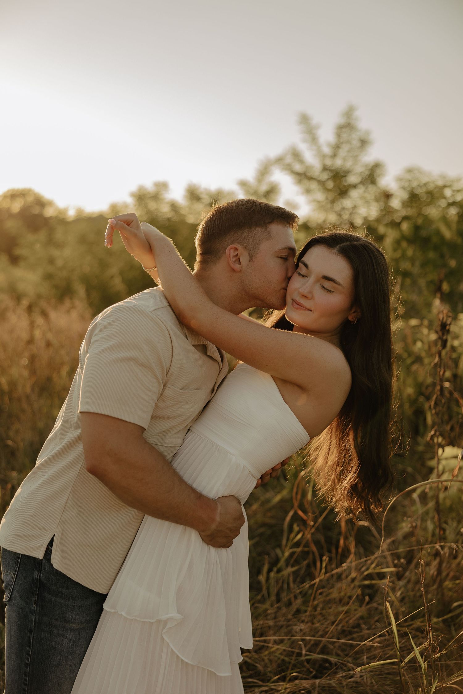 Romantic embrace captured during sunset in a field of tall grass.